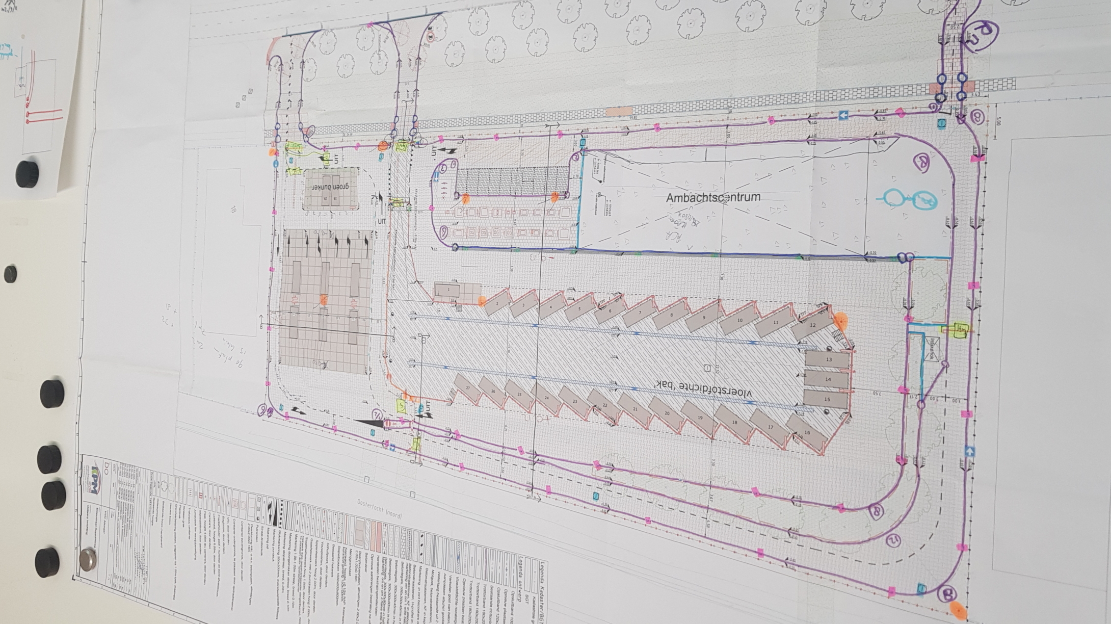 Bouwtekening van een gebouw opgehangen aan een muur met magneten.