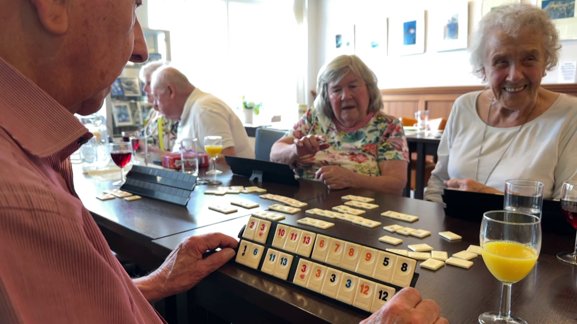 Senioren spelen een gezelschapsspel aan een tafel met drankjes.