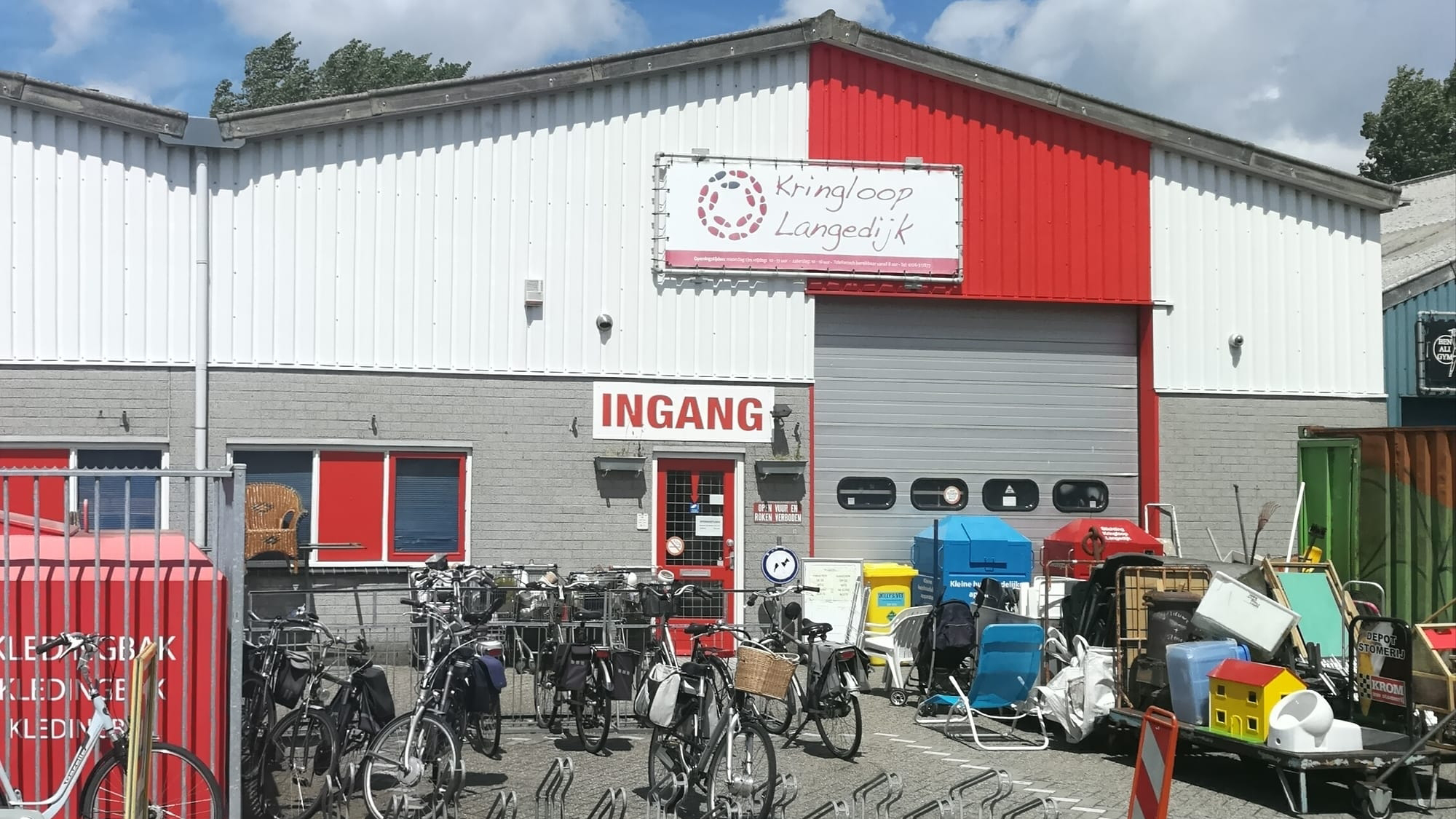 Ingang van Kringloop Langedijk met fietsen en andere items buiten.