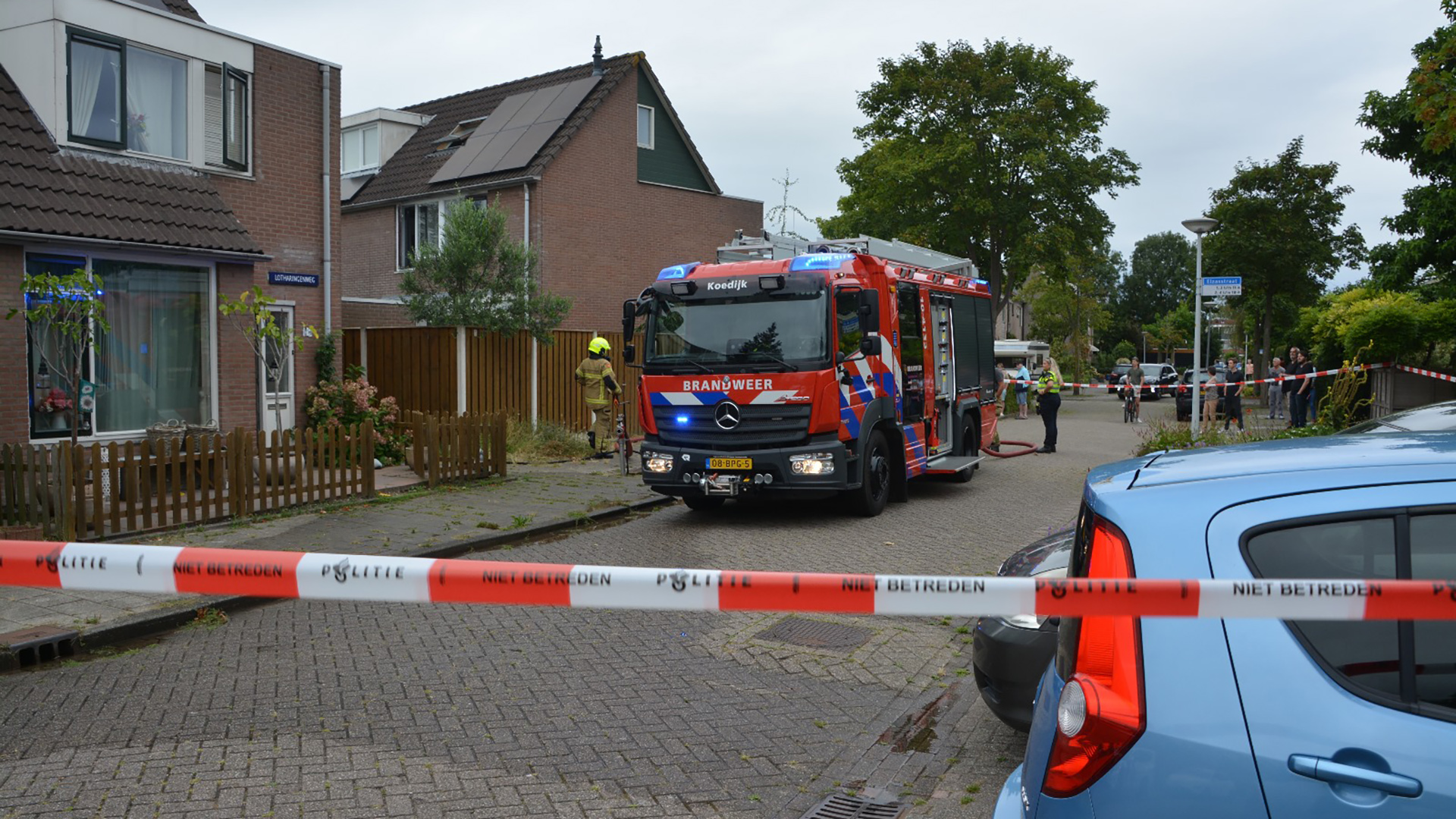 Brandweerauto en hulpdiensten bij een woning in een woonwijk, politieafzetting met linten "niet betreden".