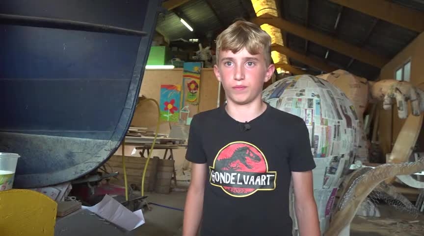 Jongen in een werkplaats draagt een zwart T-shirt met de tekst "Gondelvaart" erop.