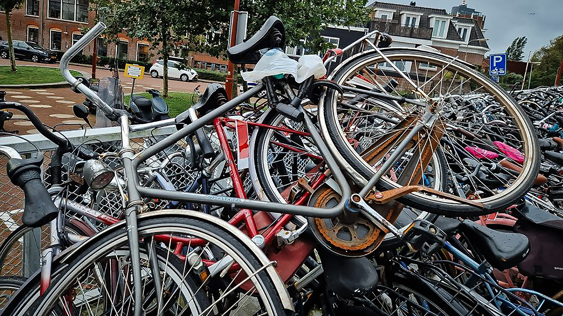 Veel fietsen rek met een stapel beschadigde en verroeste fietsen op straat.