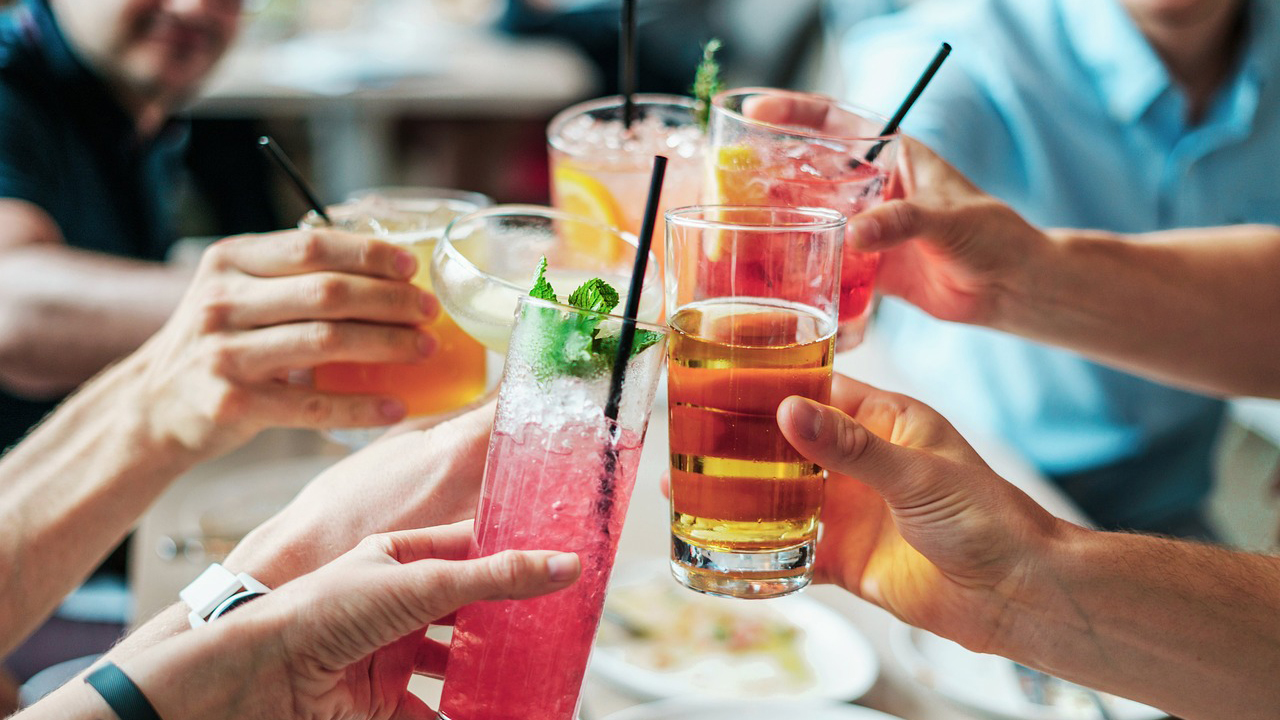 Mensen brengen een toost uit met verschillende kleurrijke drankjes.