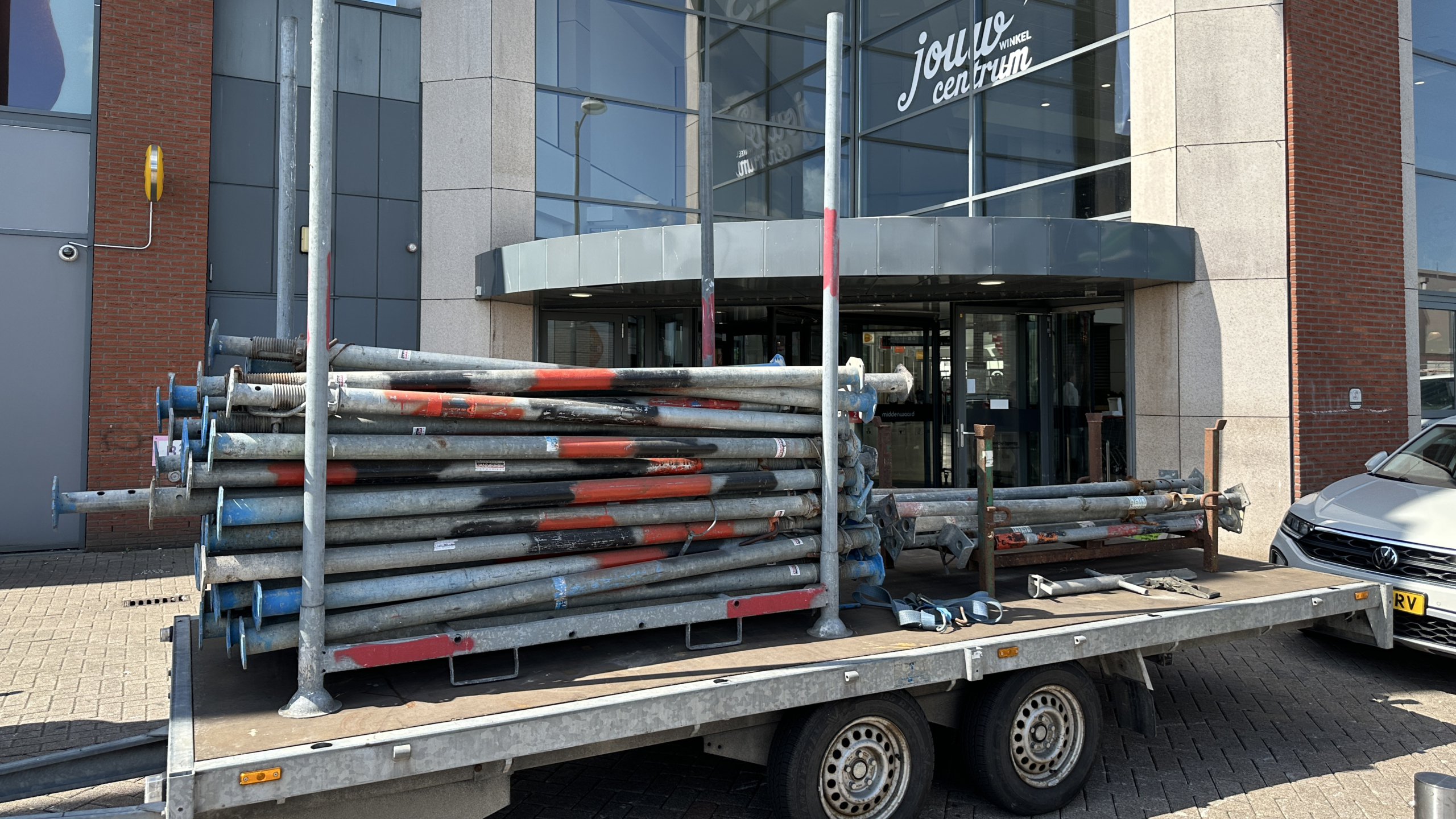 Bouwmaterialen op een aanhanger geparkeerd voor een winkelcentrum.