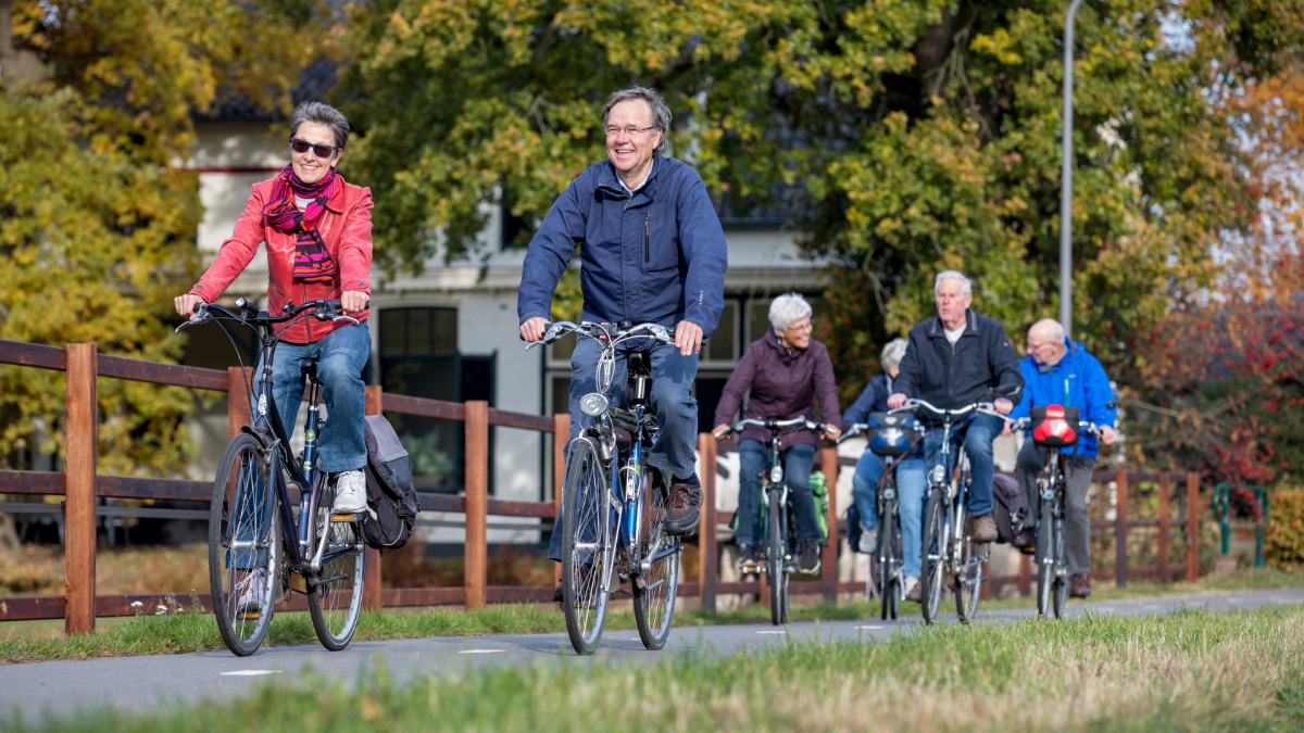 Groep ouderen fietst buiten op een zonnige dag.