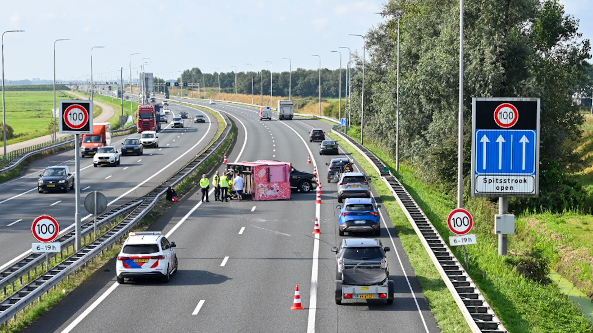 Verkeersongeluk op een snelweg met politie en voertuigen op de pechstrook.