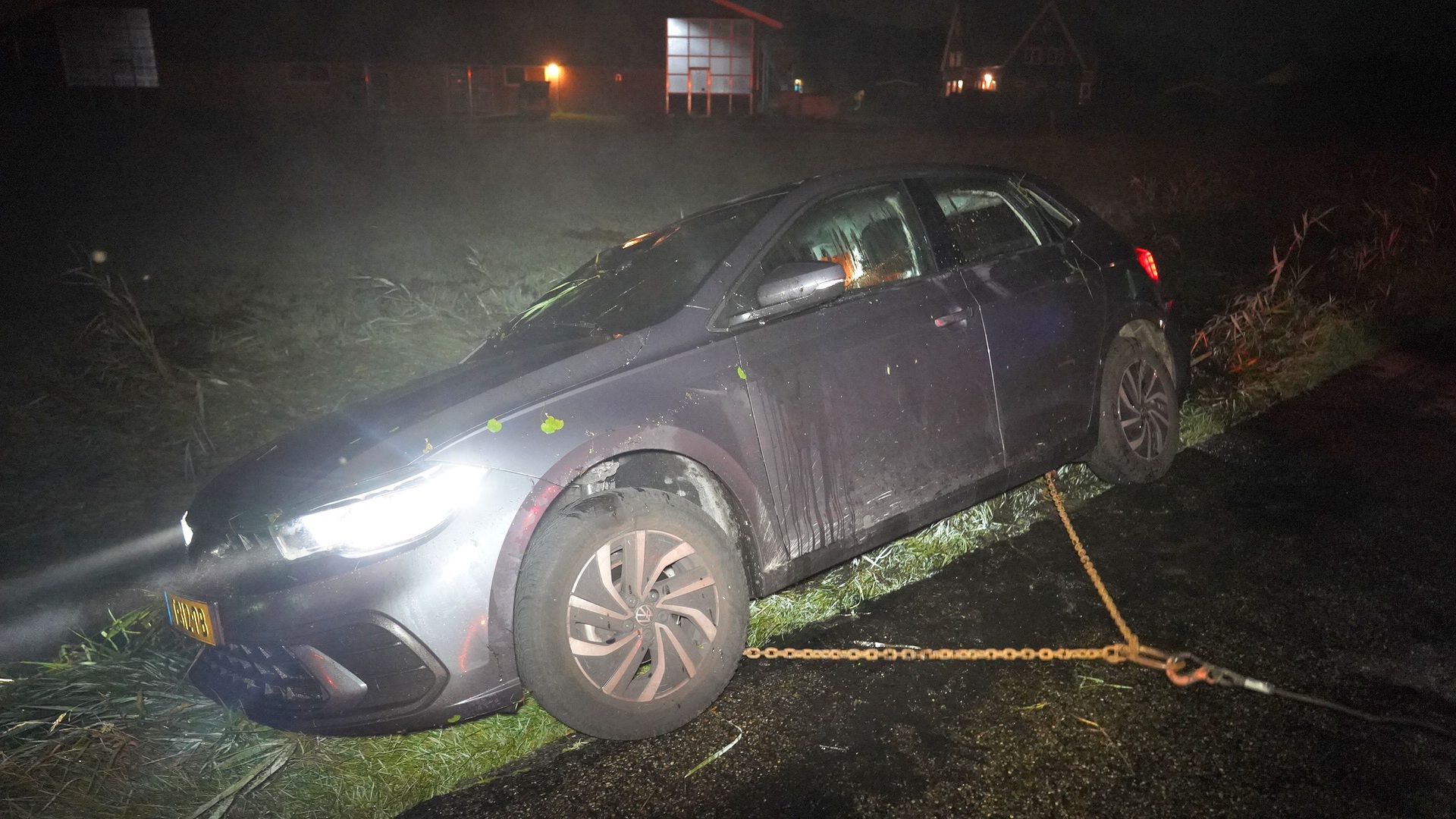 Auto vast in berm in het donker, wordt losgetrokken met touw of ketting.