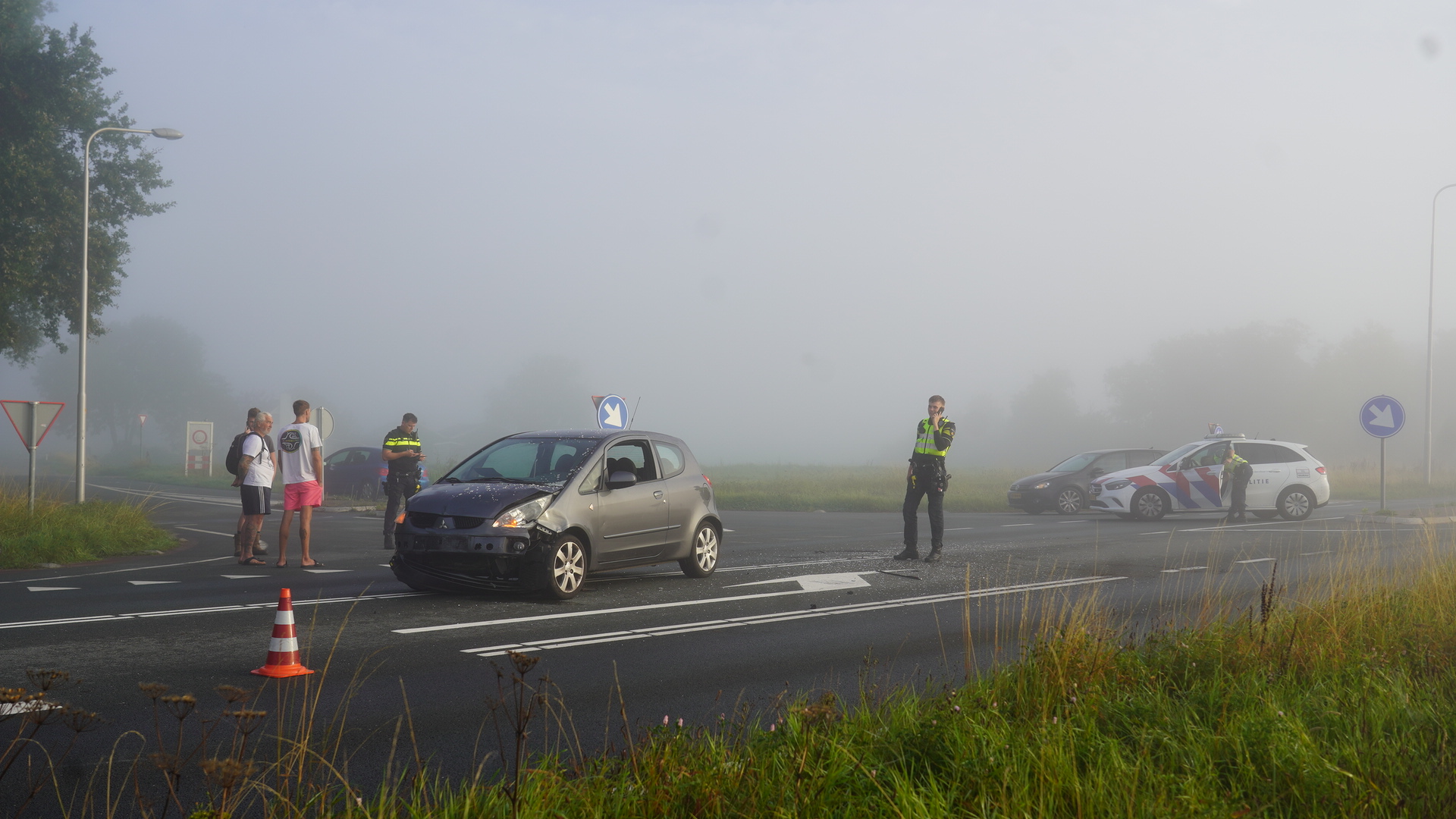 Auto-ongeluk op een mistige weg met politieagenten en omstanders.