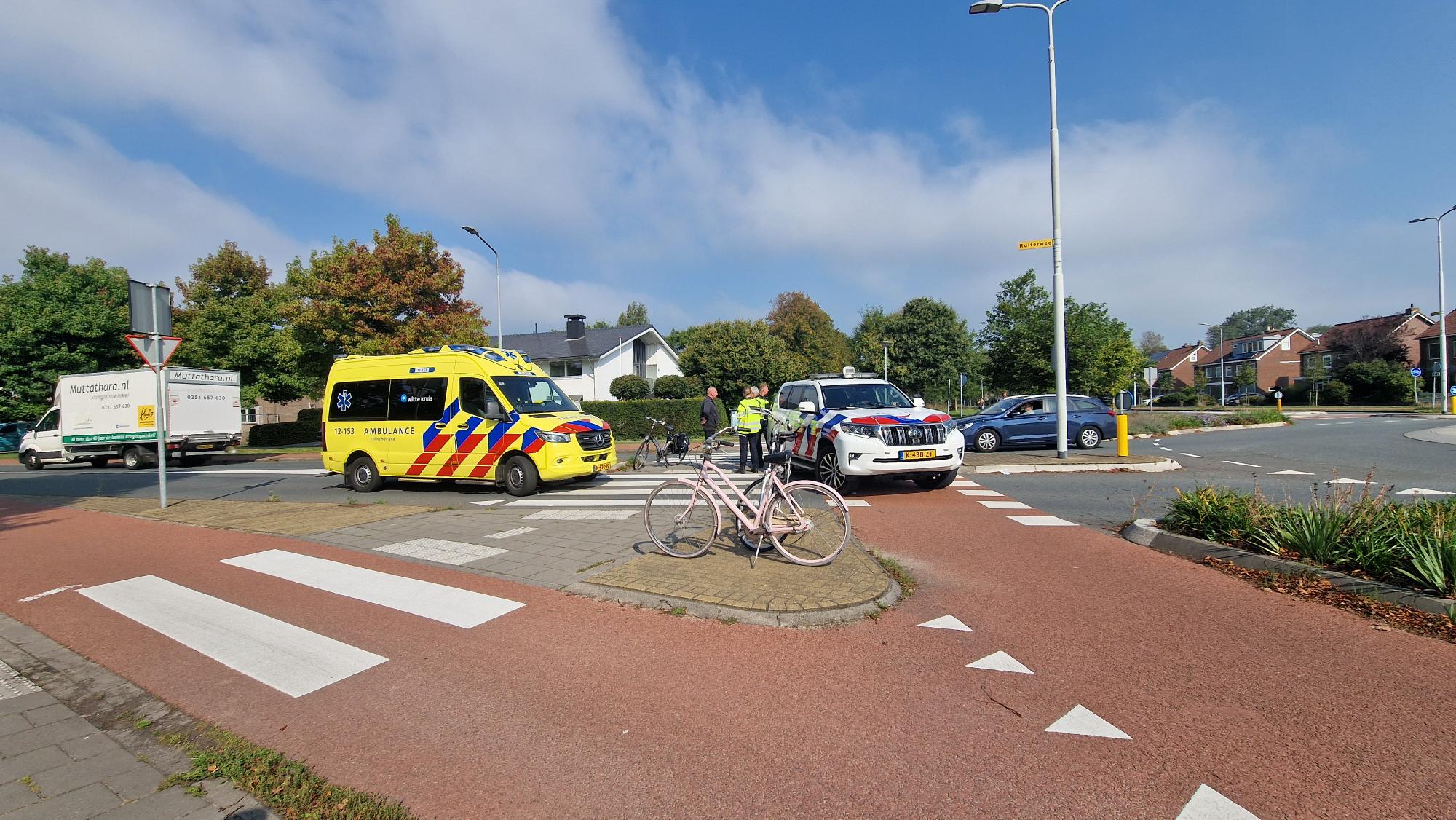 Ambulance en politiewagen bij een verkeersongeluk met fietsers op een rotonde.