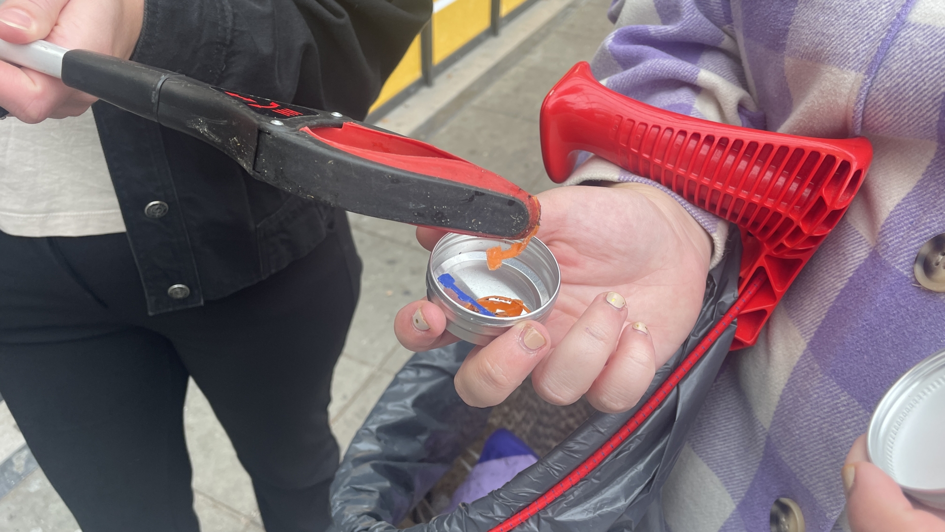 Twee mensen peeling plastic afval van straat met grijpstok.