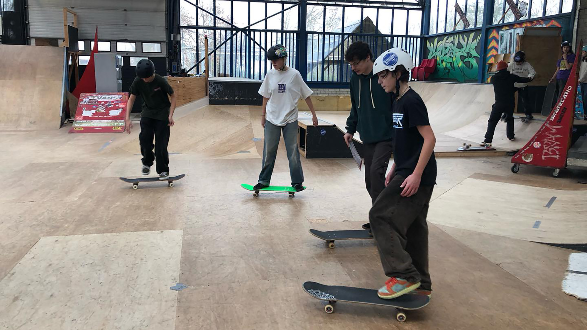 Mensen skateboarden in een indoor skatepark.