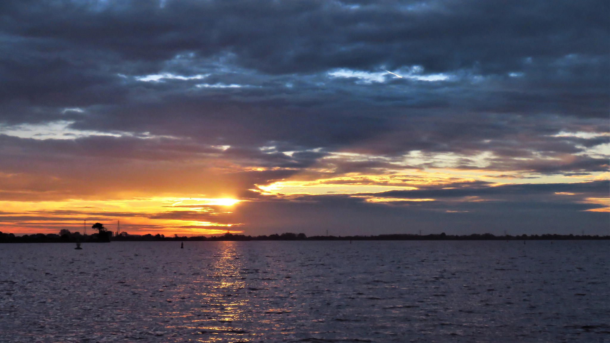 Zonsondergang boven een meer met bewolkte lucht.