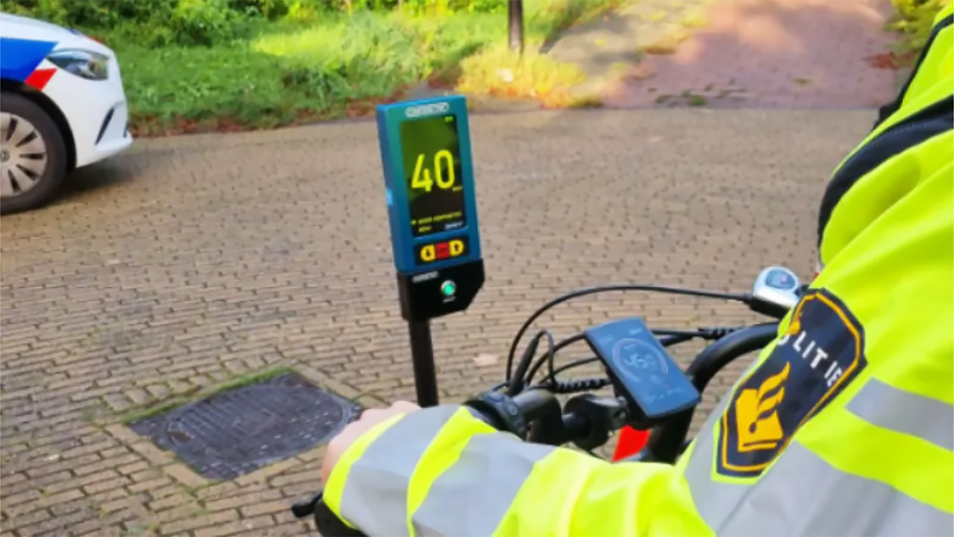 Politieagent op een fiets meet de snelheid van voorbijrijdende voertuigen met een snelheidsmeter die 40 km/u aangeeft.