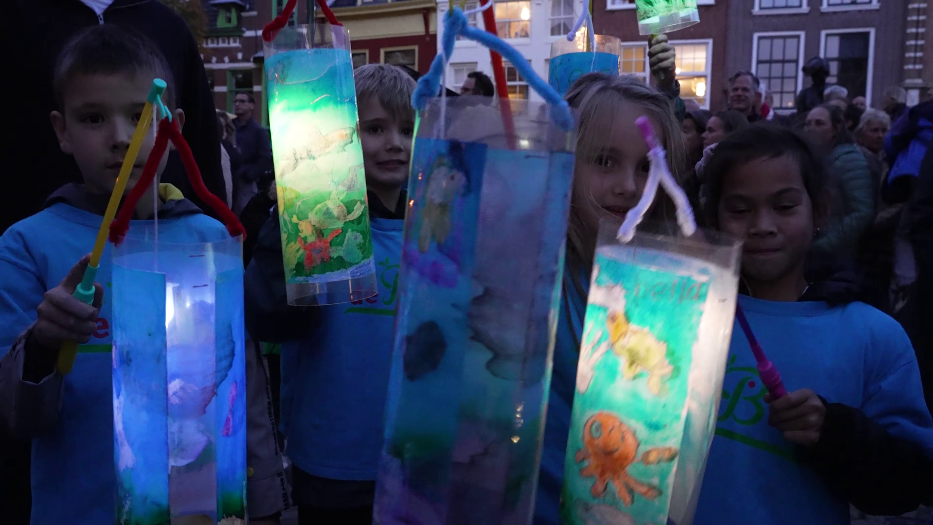 Kinderen houden zelfgemaakte lantaarns vast tijdens een optocht in de avond.