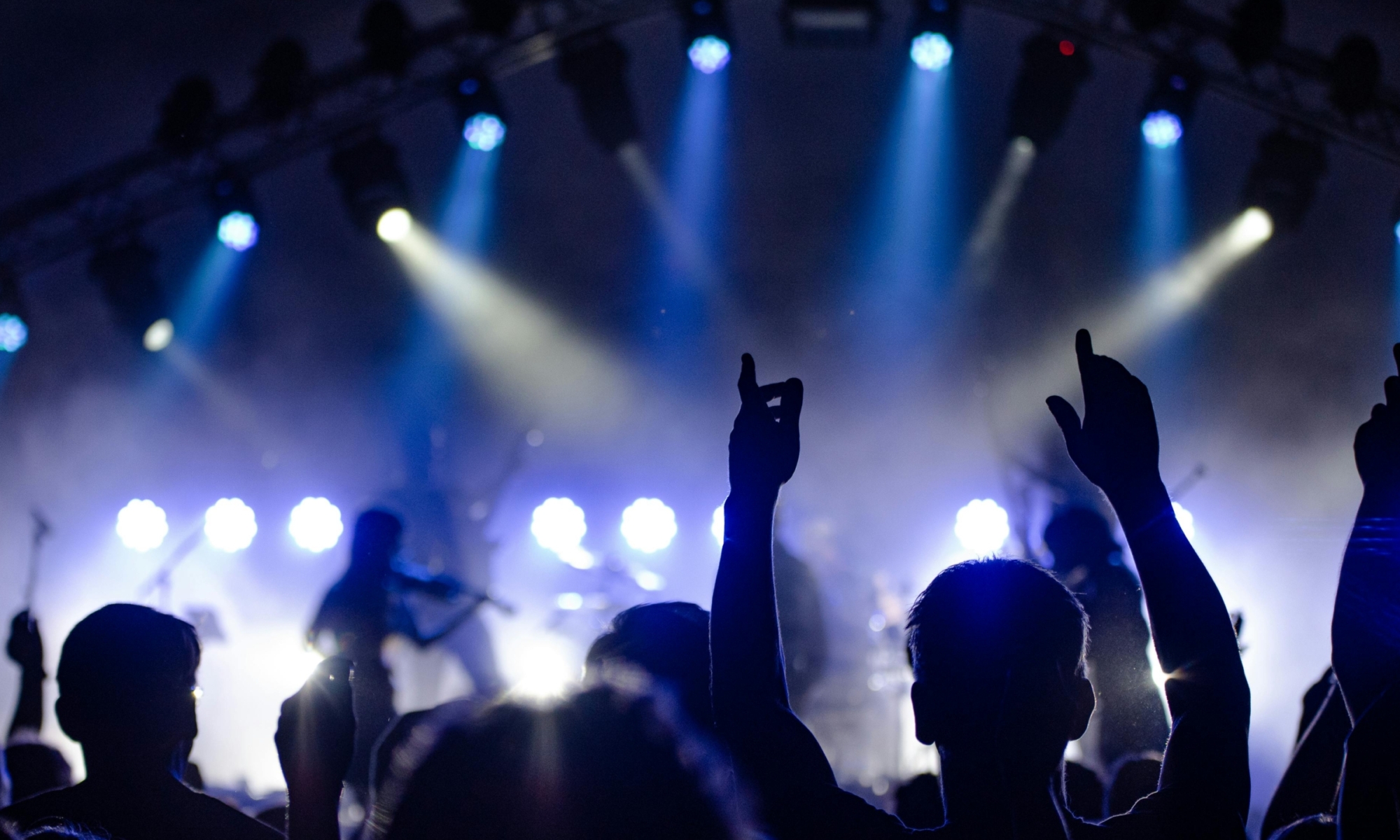 Publiek bij een concert met felle blauwe en witte podiumlichten.