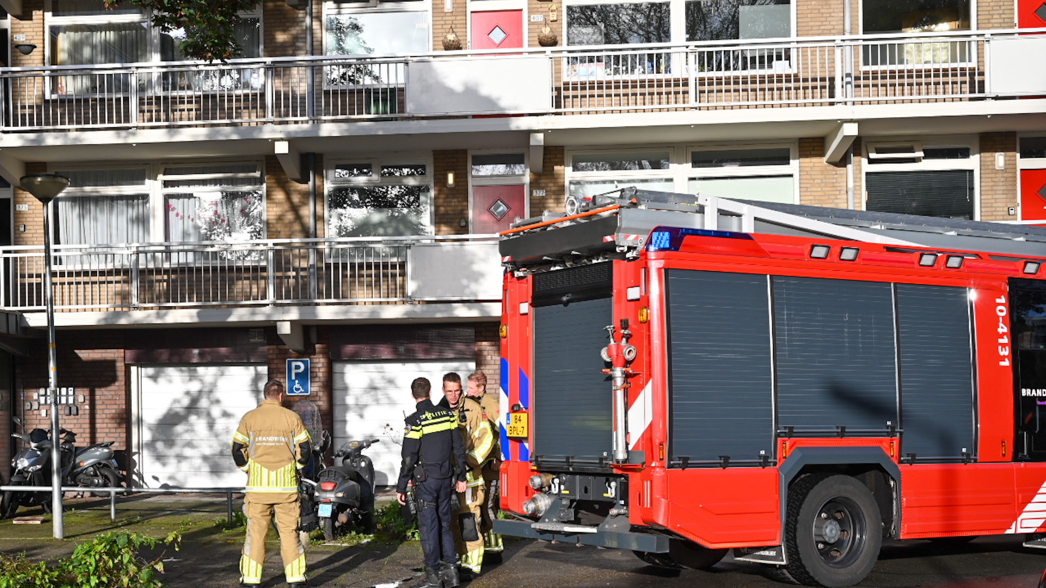 Brandweerwagen en brandweerlieden voor een appartementencomplex.