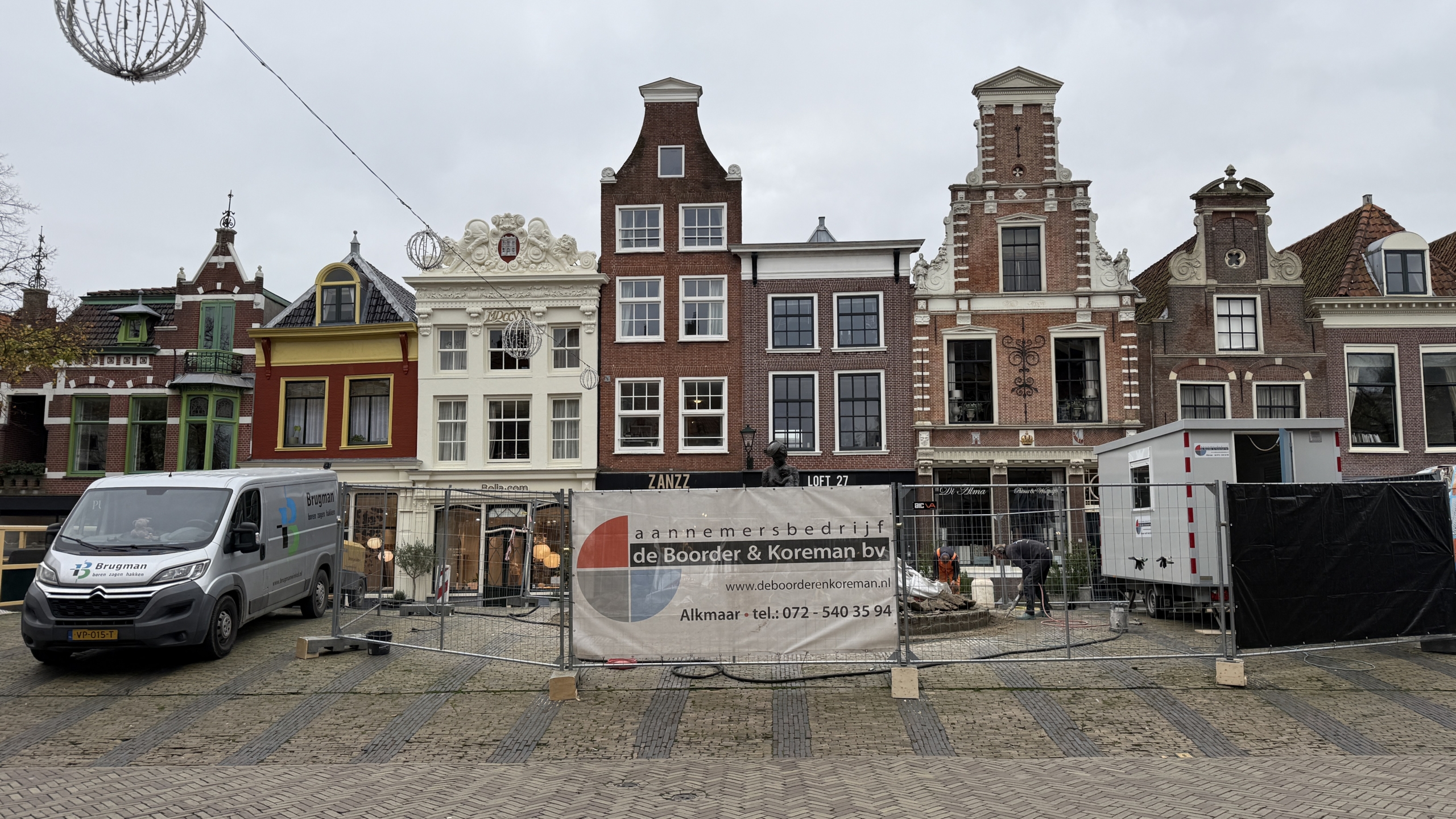 Historische gevels in Alkmaar met bouwplaats en bedrijfsbusje op de voorgrond.