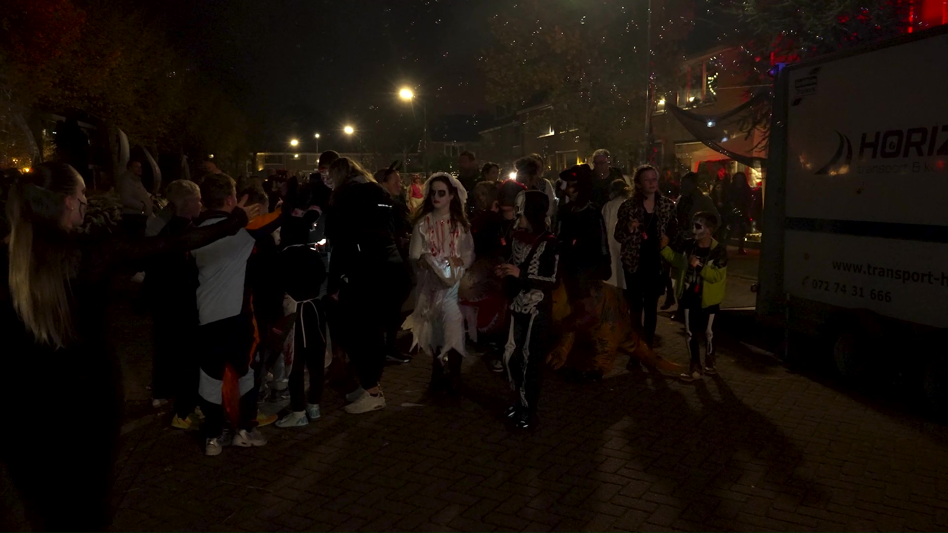 Groep mensen in Halloween-kostuums op een donker straatfeest.