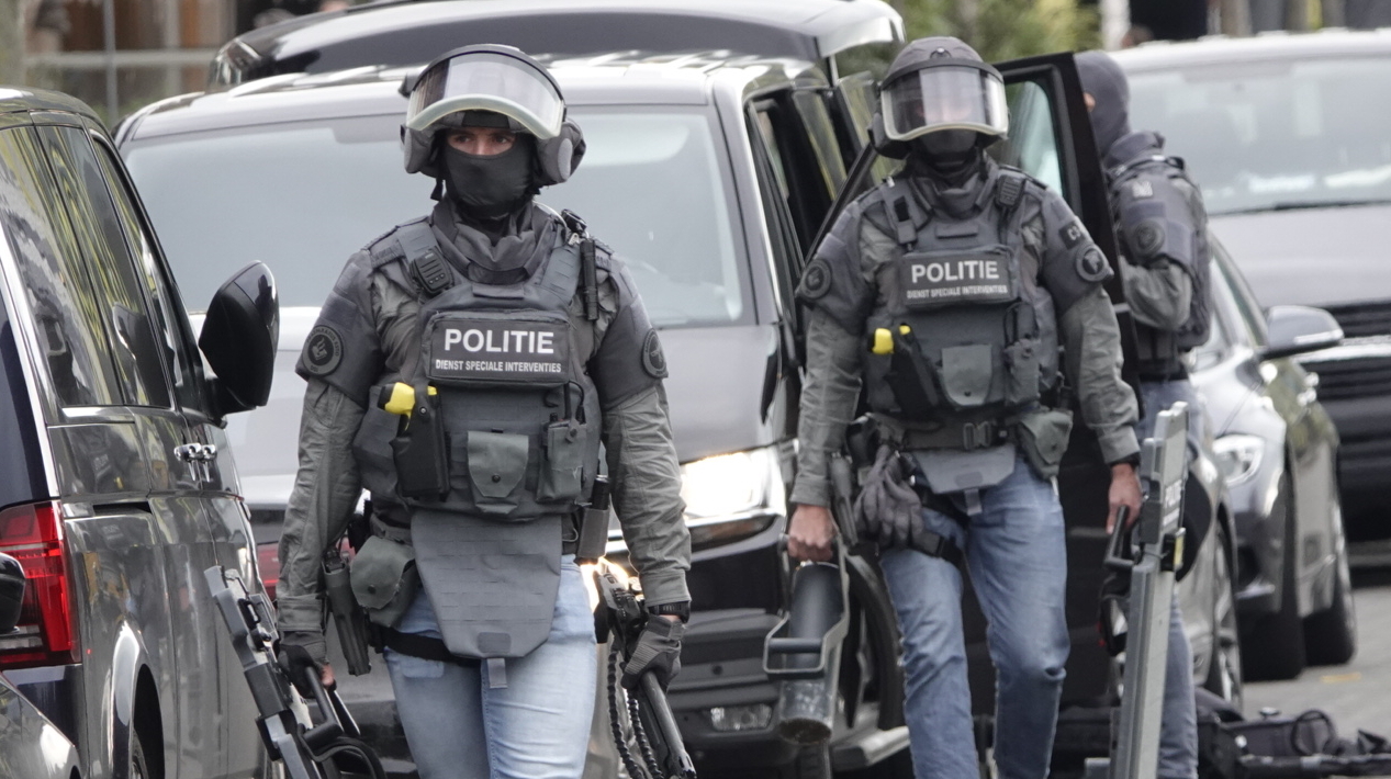 Gewapende politieagenten in tactisch uniform lopen in een straat.