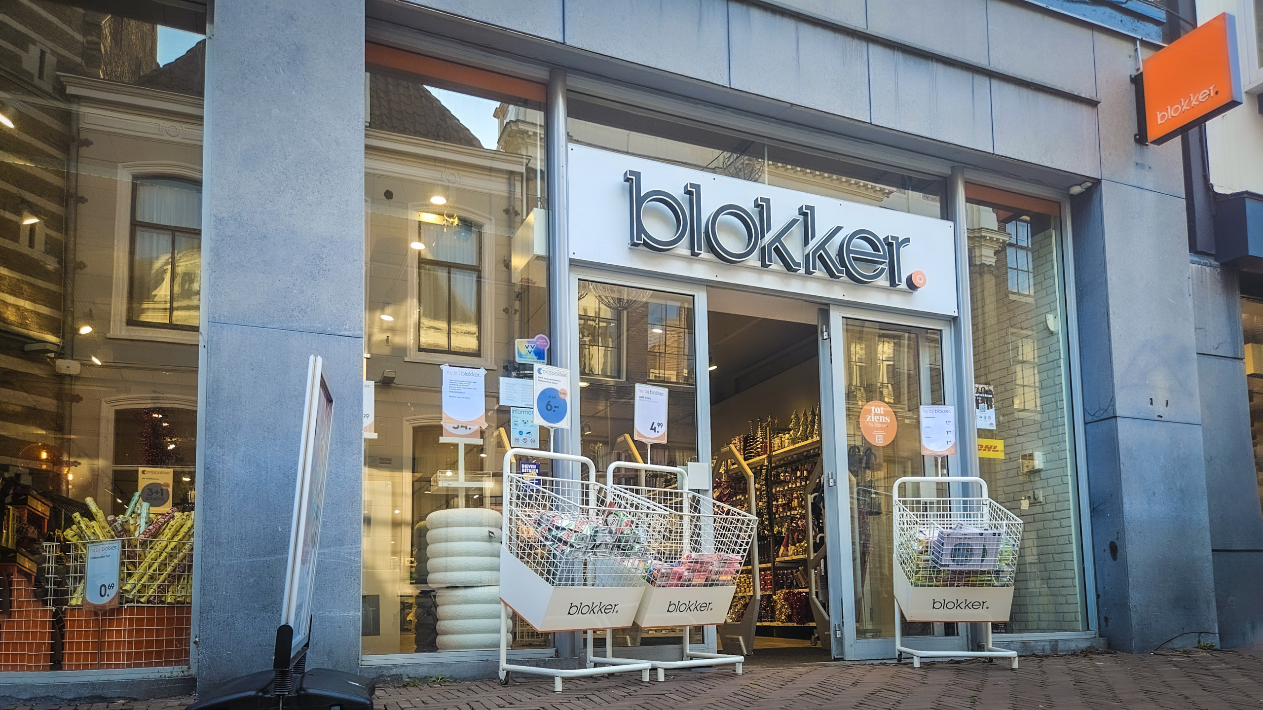 Buitenaanzicht van een Blokker-winkel met open deuren en winkelmanden bij de ingang.