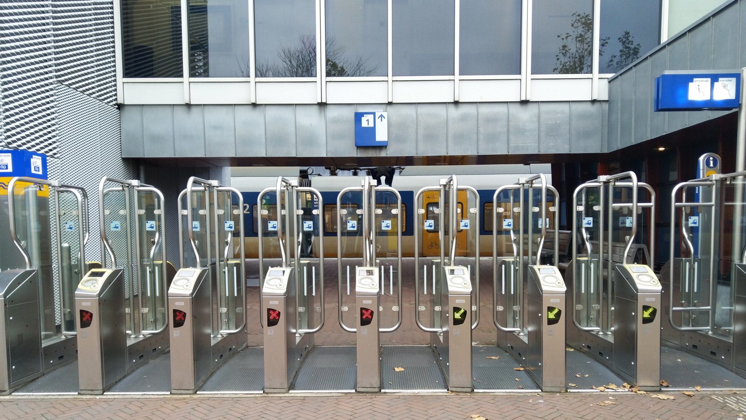 Toegangspoortjes bij een treinstation met een trein op de achtergrond.