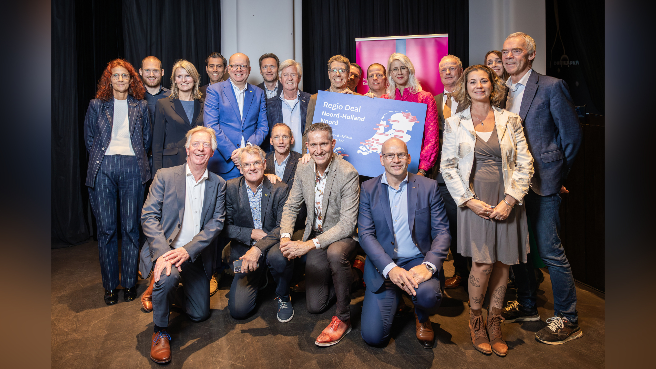 Een groep mensen poseert samen voor een foto met een bord met de tekst "Regio Deal Noord-Holland Noord".