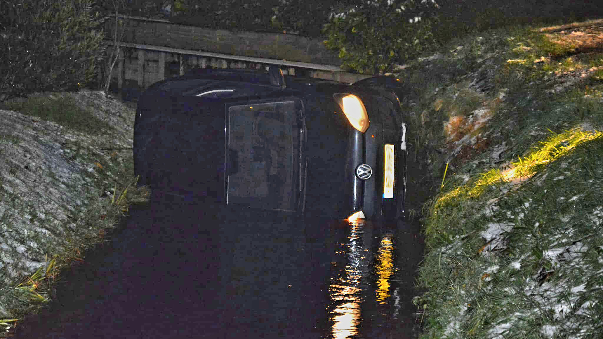 Auto op zijn zijkant in een sloot.