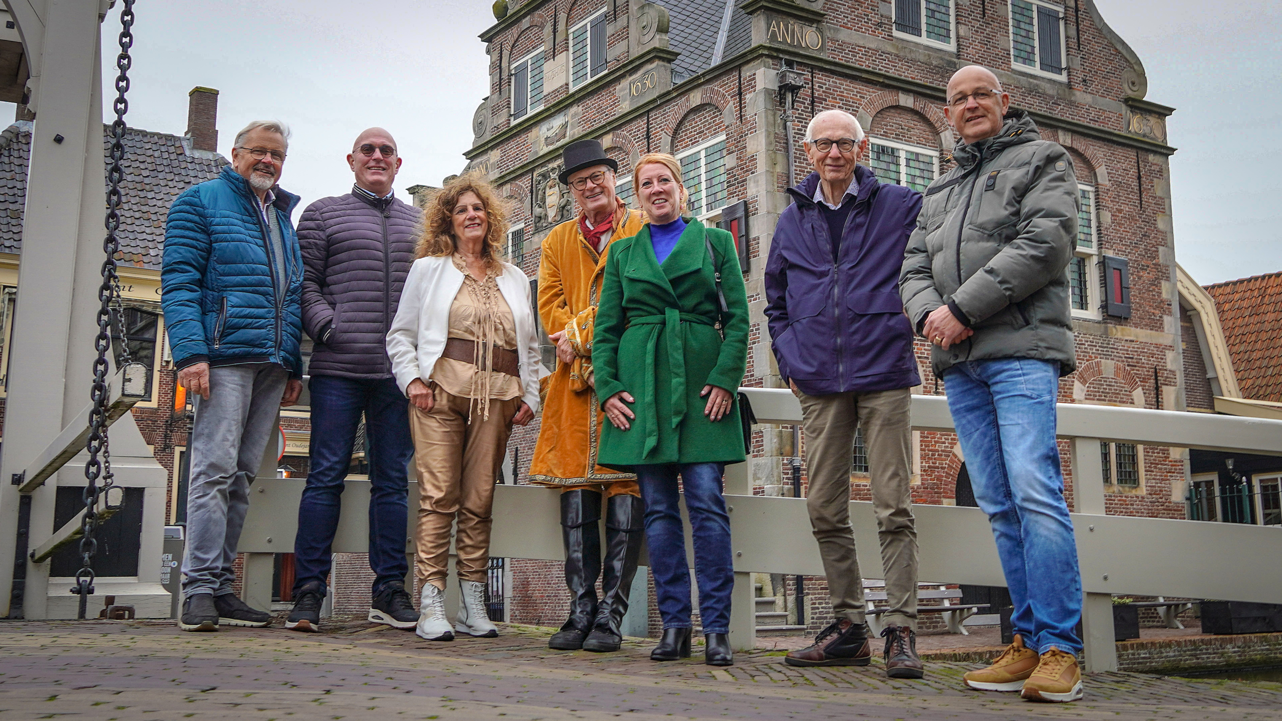 Groep mensen poseert op een brug voor een historisch gebouw.