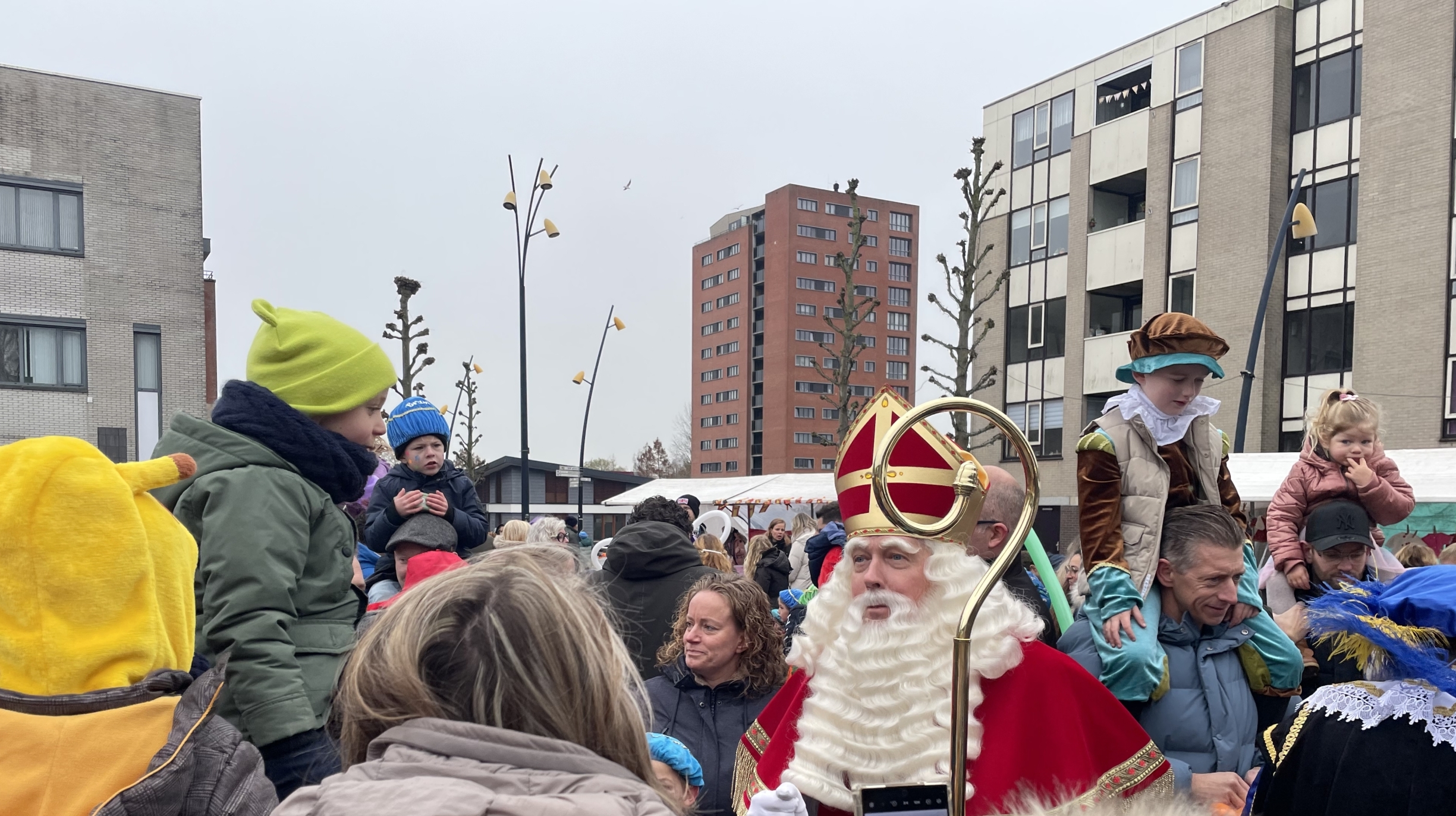 Sinterklaas en Pieten te midden van een menigte mensen op een plein.