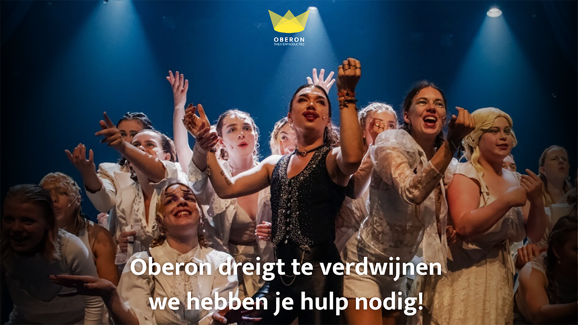 Groep jongeren in theatrale kostuums op een podium met de tekst "Oberon dreigt te verdwijnen, we hebben je hulp nodig!".