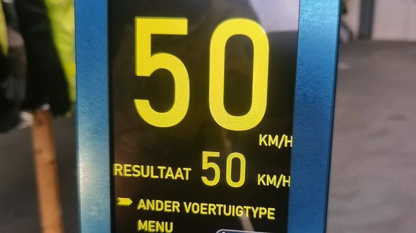 Digitale snelheidsmeter met de aanduiding "50 km/h", "RESULTAAT 50 km/h", en opties voor "ANDER VOERTUIGTYPE" en "MENU".