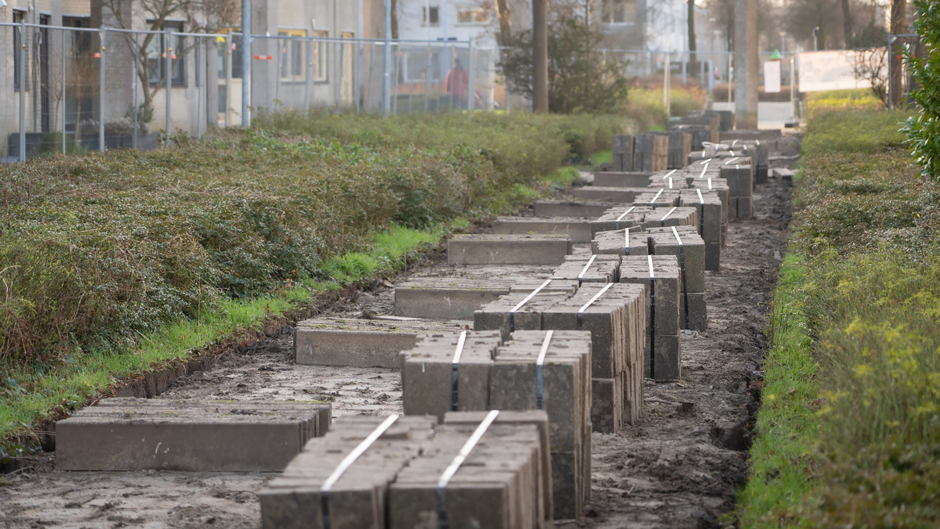 Stapel betonnen stenen langs een onverharde weg tussen struiken.