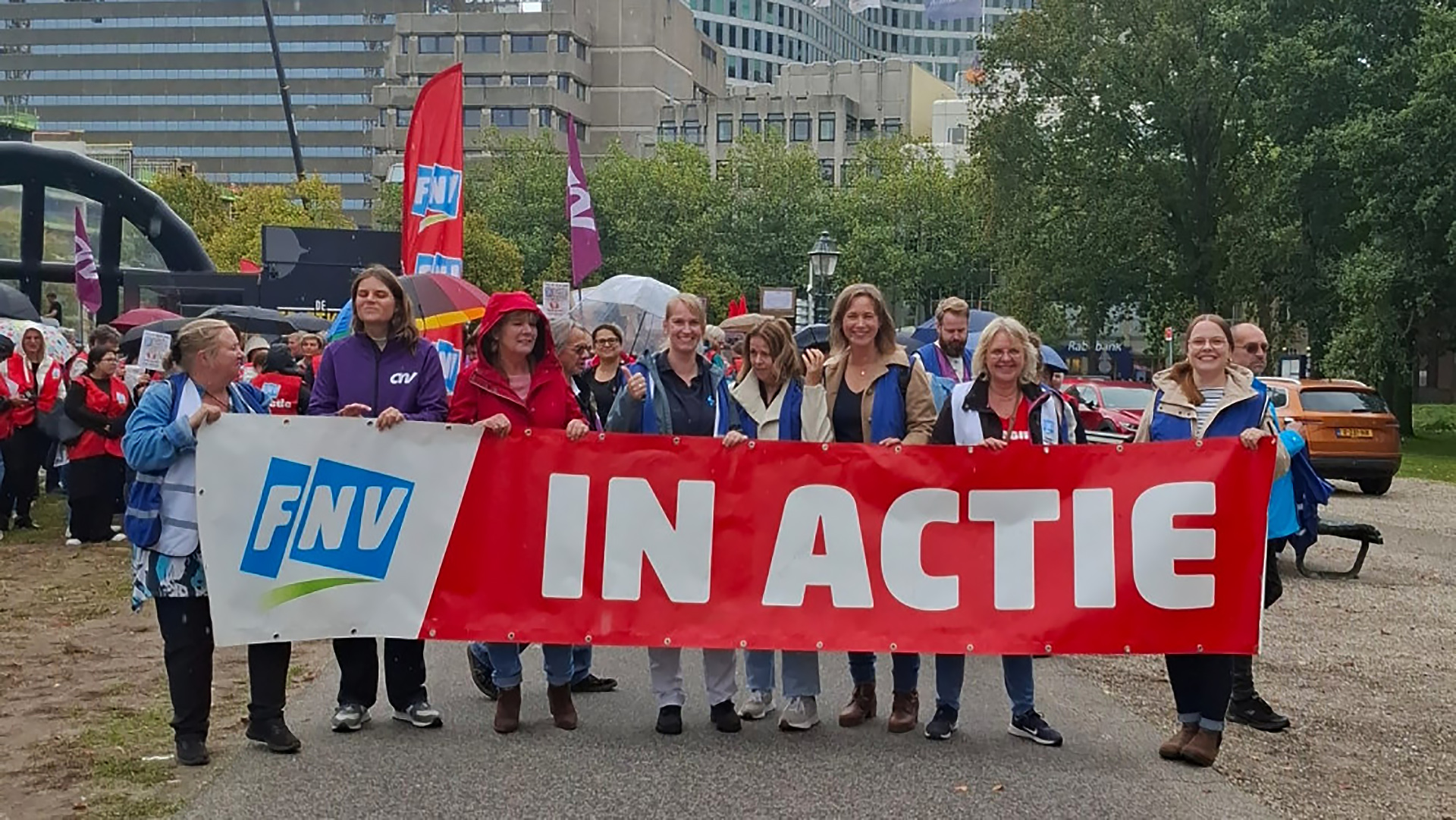 Mensen lopen met een FNV-spandoek met de tekst "In Actie" tijdens een protest.