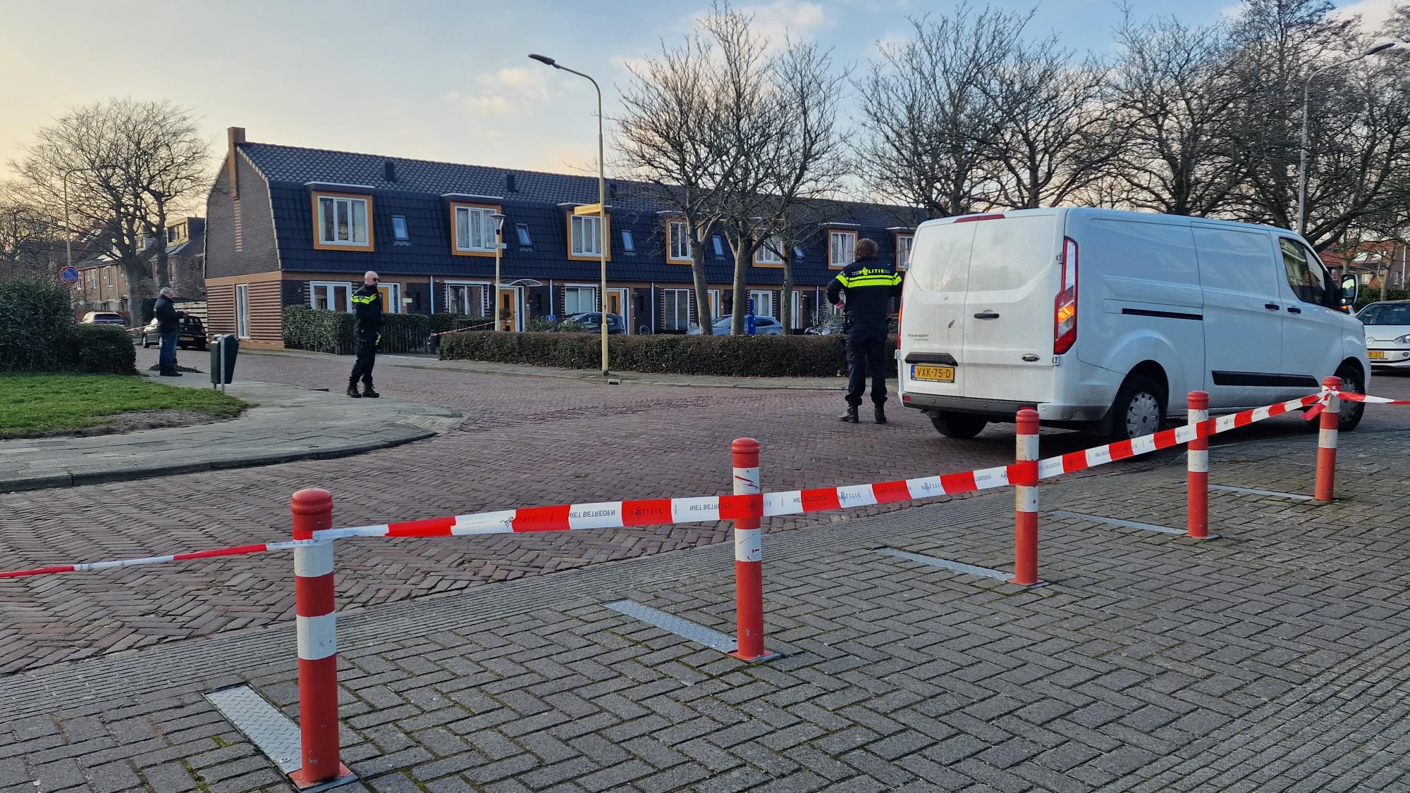 Politie zet een gebied af met lint bij een witte bestelwagen in een woonwijk.