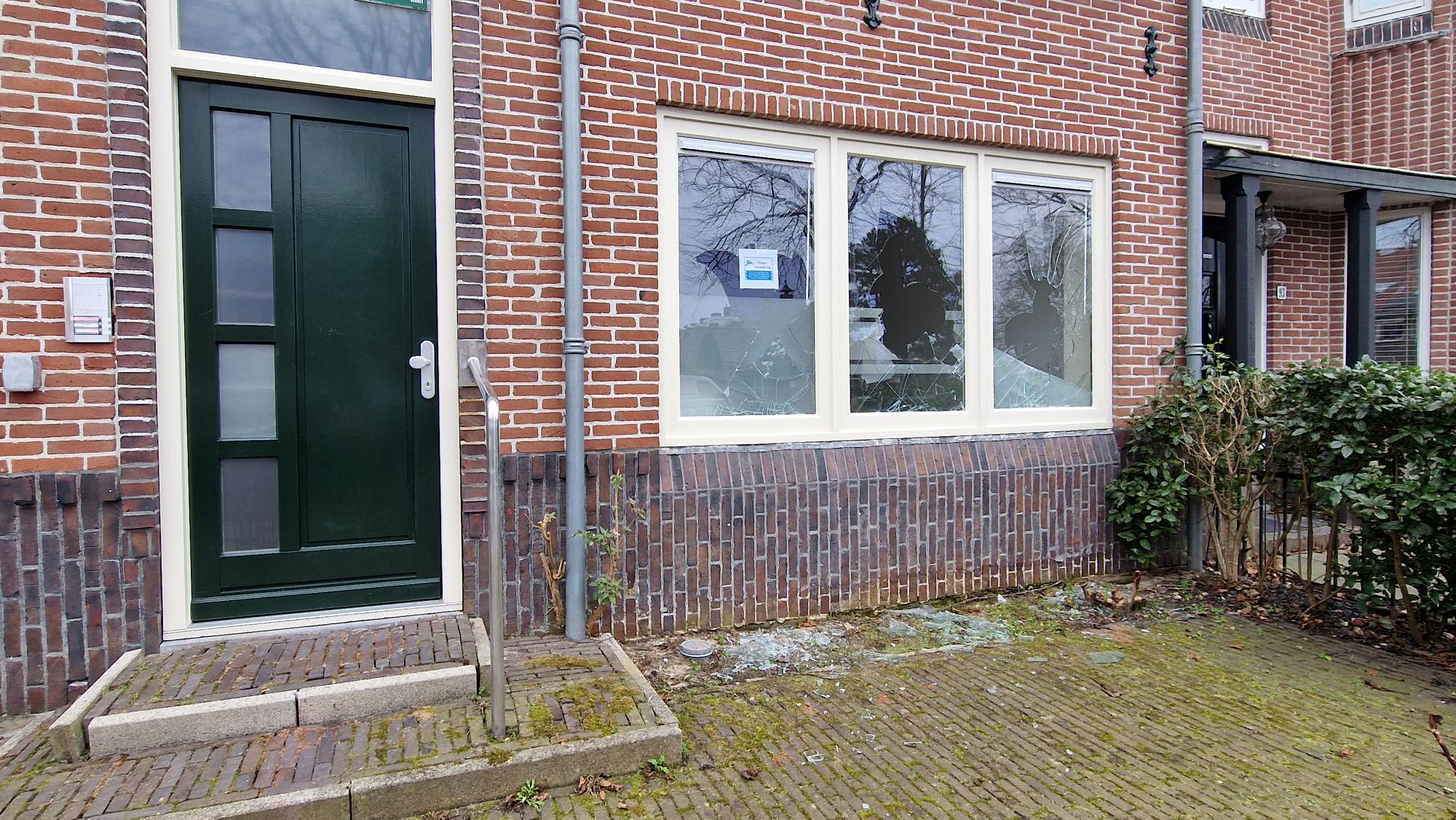 Voordeur en vensters van bakstenen huis, venster is gebarsten.