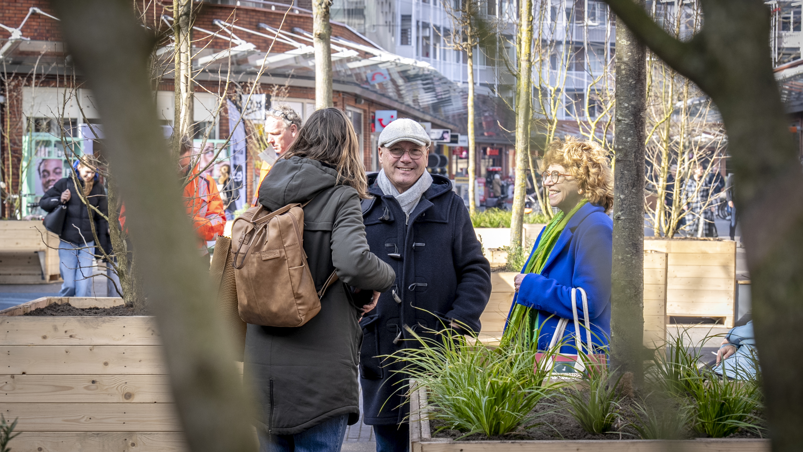 Groepje mensen in gesprek tussen bomen in een stadstuin.