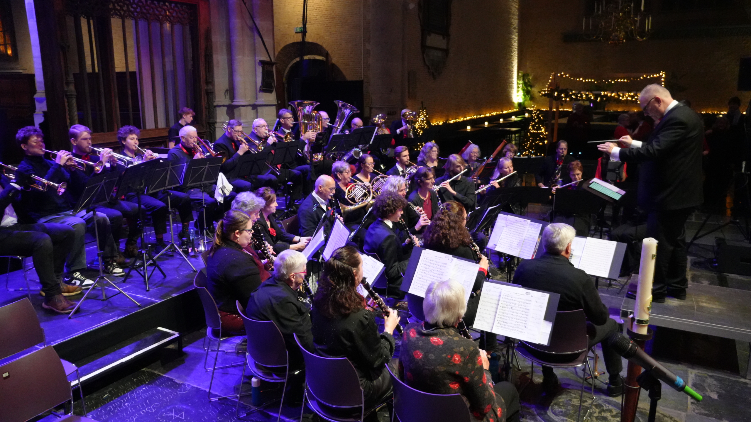 Orkest speelt muziek onder leiding van dirigent in een verlichte zaal.