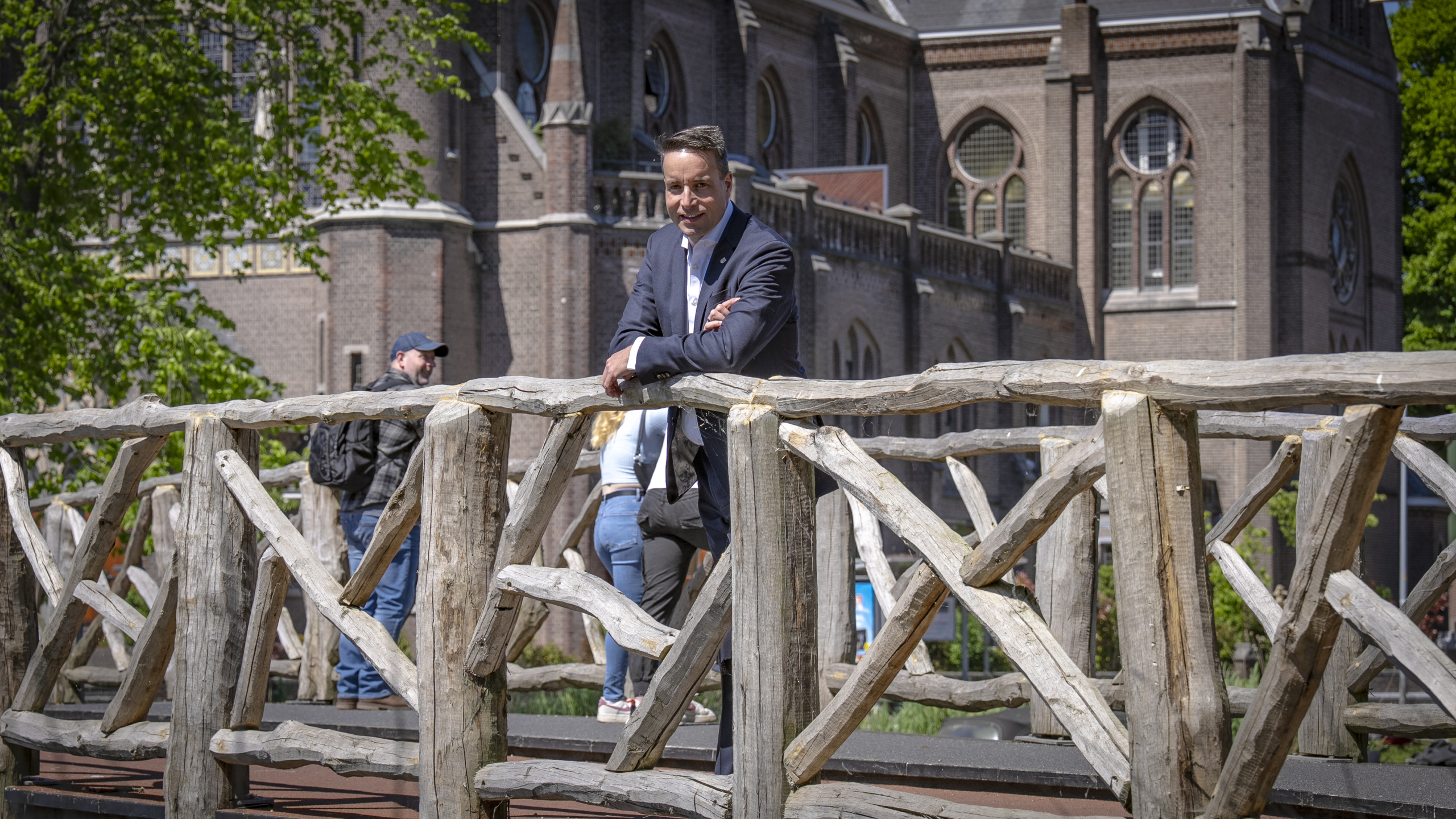Man leunt op een rustiek houten hek met een kerkgebouw op de achtergrond.