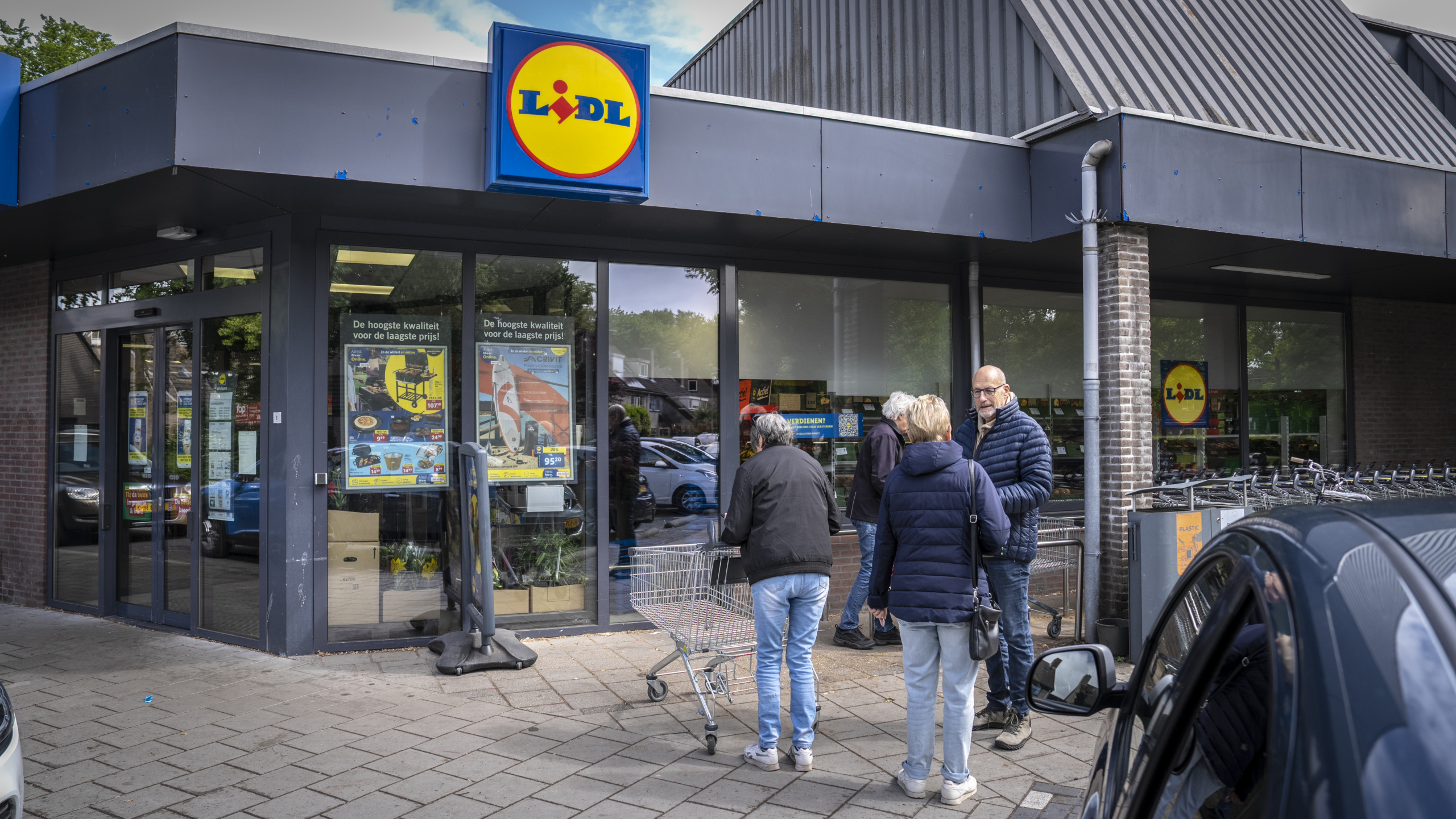 Mensen staan met winkelwagentjes voor de ingang van een Lidl-supermarkt.