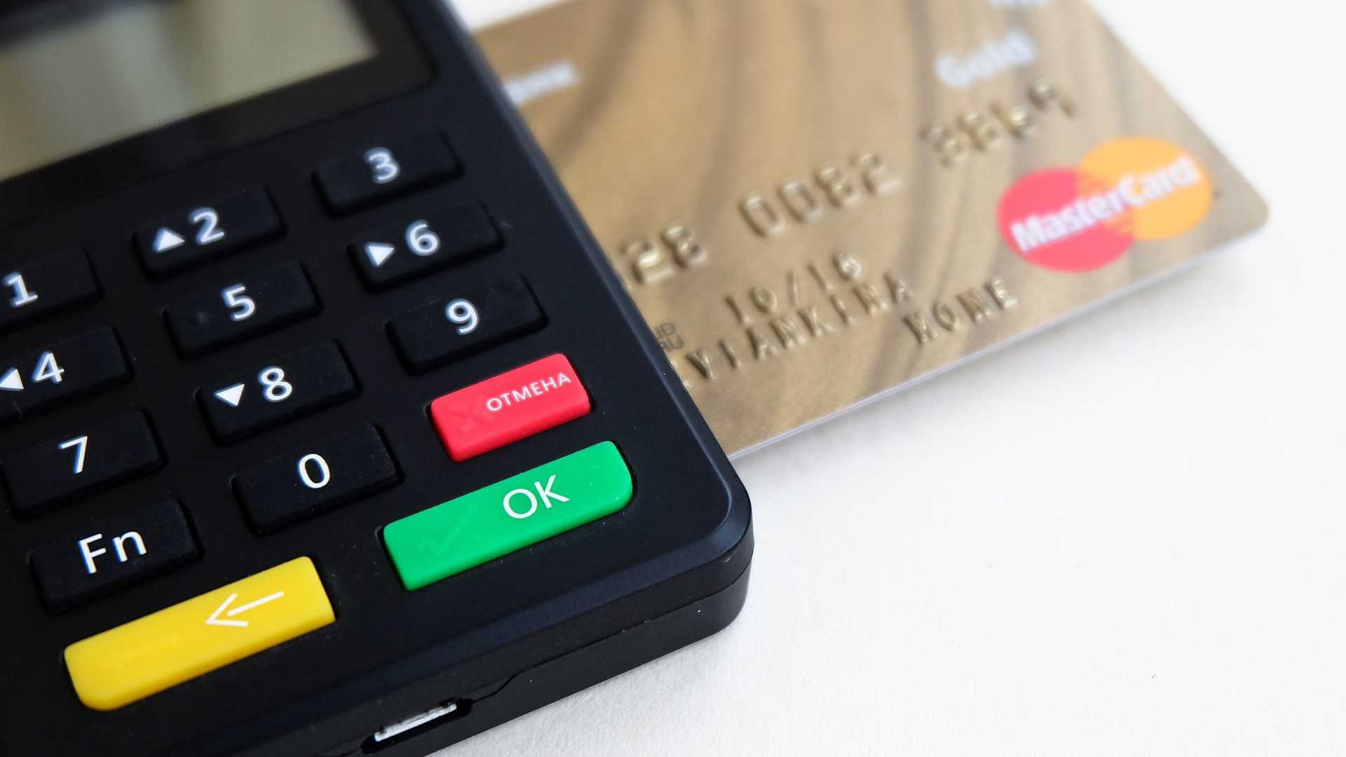 Zwarte betaalterminal met toetsen en een bankkaart met MasterCard-logo.