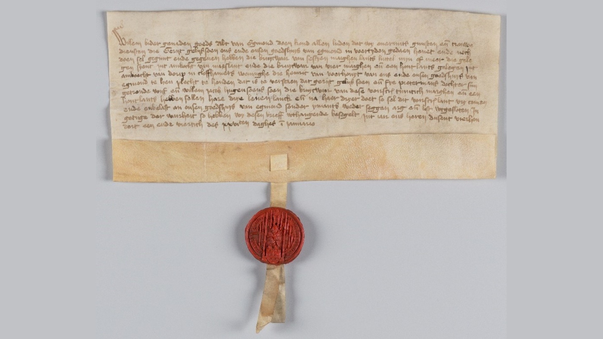 Een oude handgeschreven oorkonde met een waszegel eraan bevestigd. Het document is op perkament geschreven en het rode zegel toont een reliëf van een figuur.