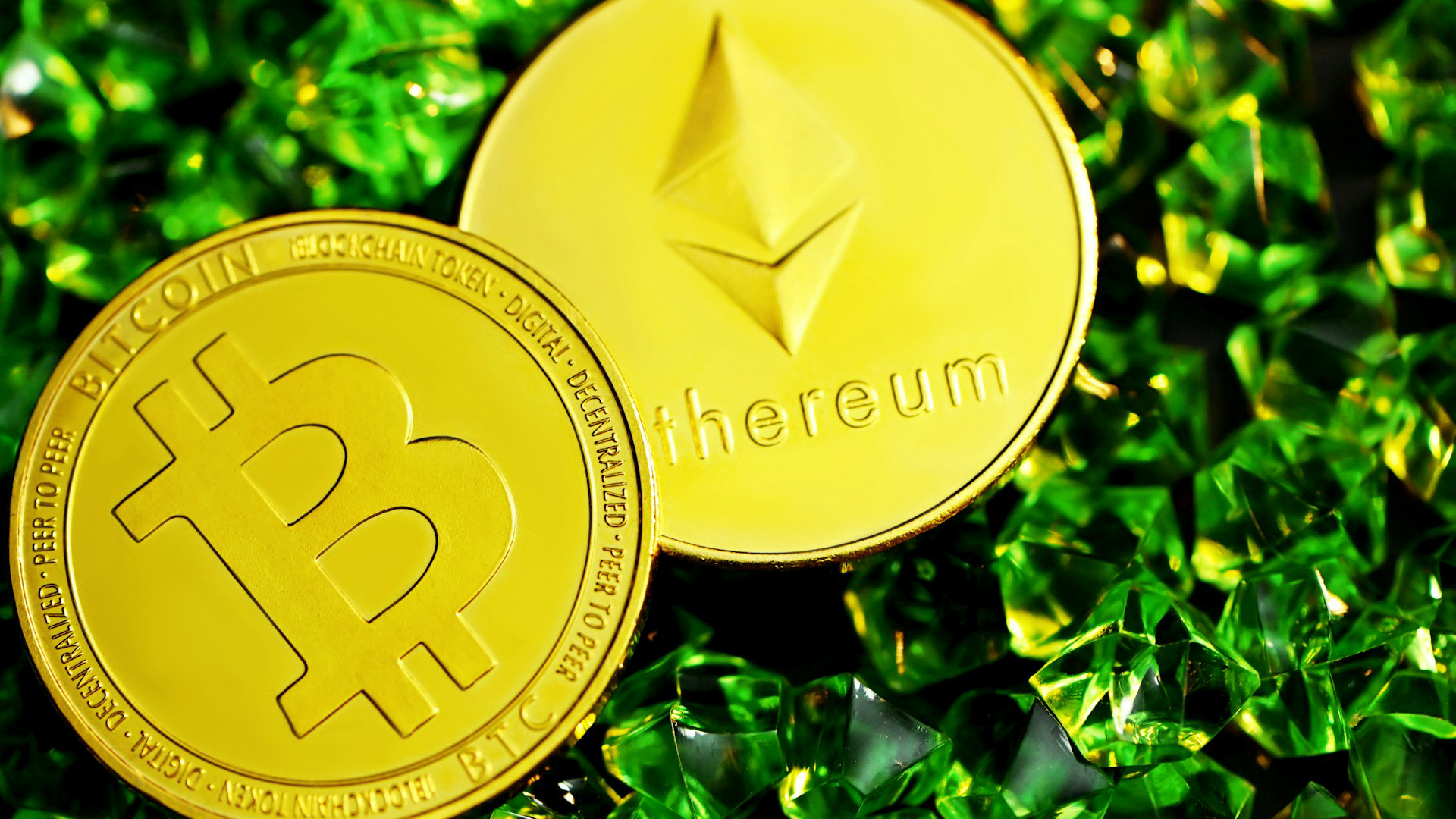 Twee gouden munten met het Bitcoin- en Ethereum-logo liggen op een achtergrond van groene kristallen.