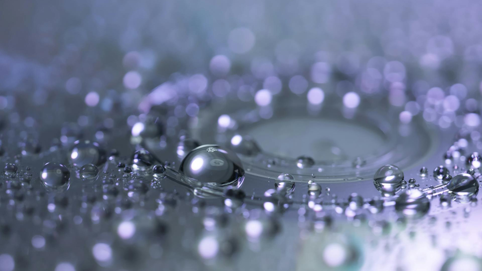 Waterdruppels in macrofotografie op een glad oppervlak, met een paarse en zilveren gloed en zachte onscherpe achtergrond.
