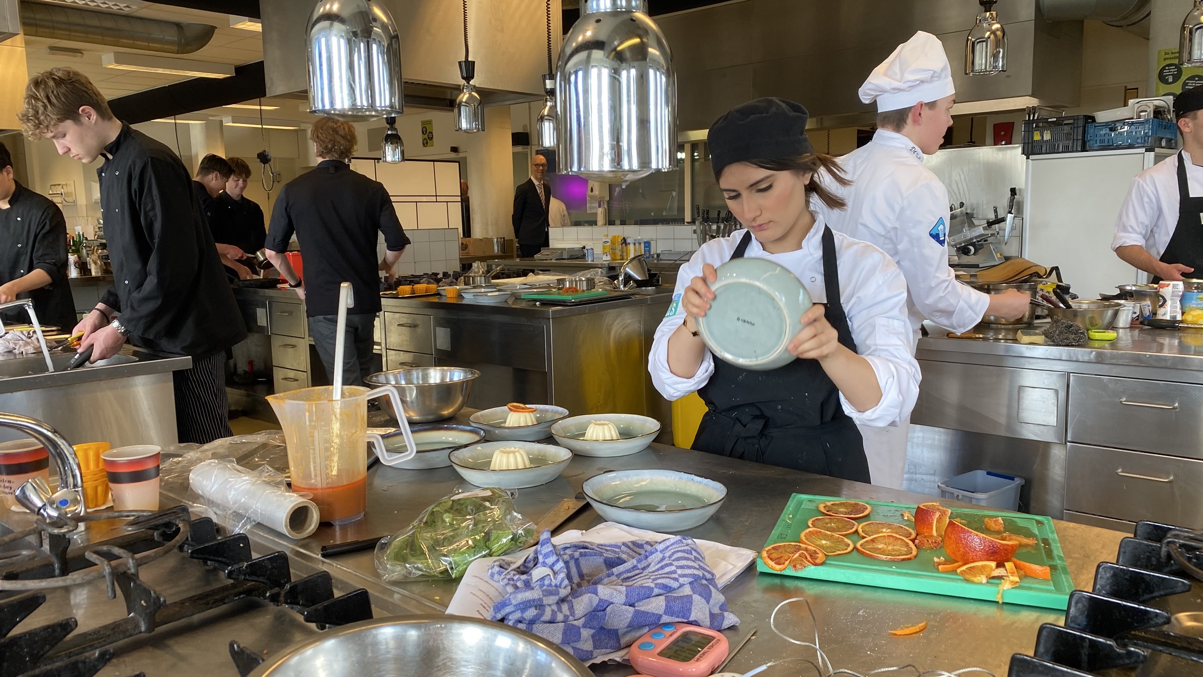 Koks en kokkinnen werken in een professionele keuken, groenten snijdend en gerechten voorbereidend.
