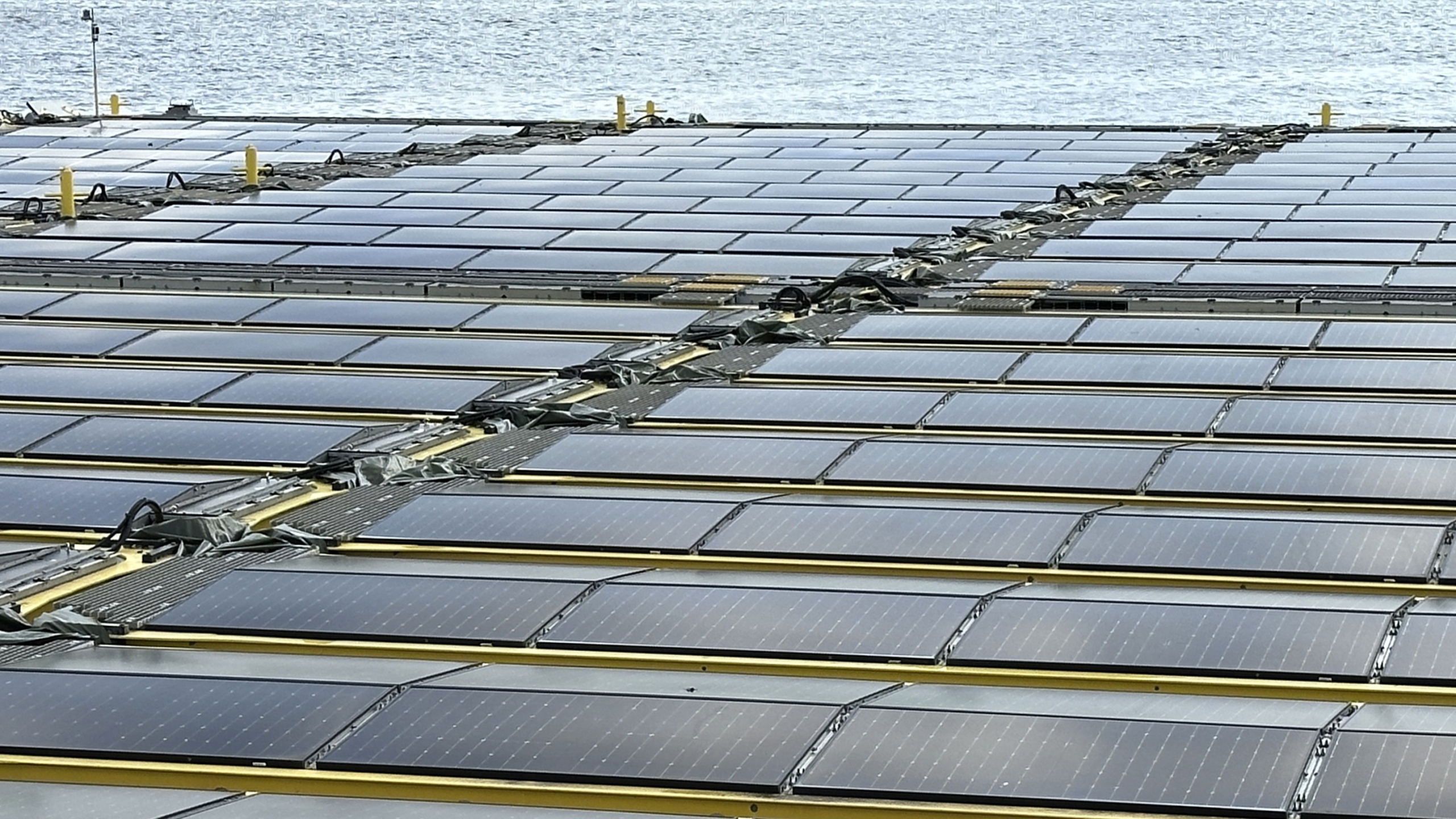 Rij zonnepanelen op een groot drijvend platform op het water.