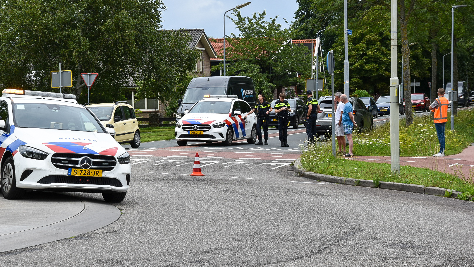 Politieauto's en agenten staan bij een verkeersongeluk met auto's geblokkeerd op de weg.