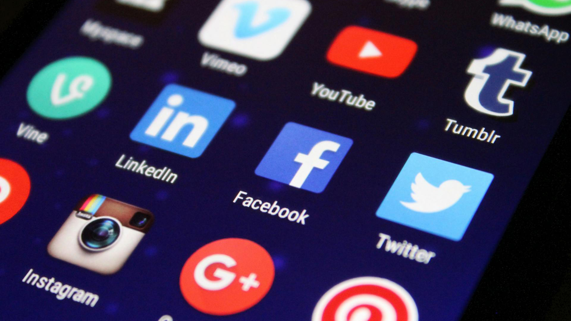 Close-up van een smartphonebeeldscherm met verschillende sociale media en app-iconen, waaronder Twitter, Facebook, LinkedIn, YouTube, Instagram, en meer.
