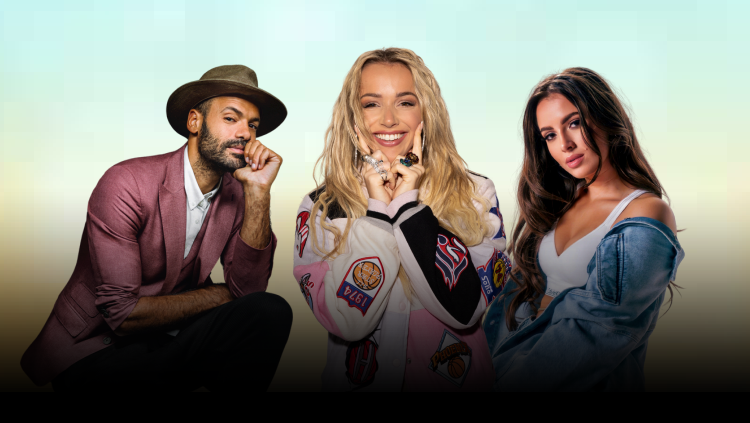 Twee vrouwen en een man poseren voor een neutrale achtergrond; de man draagt een hoed en een roze blazer, de blonde vrouw draagt een wit jasje met patches, en de brunette heeft een denim jack over een wit topje.
