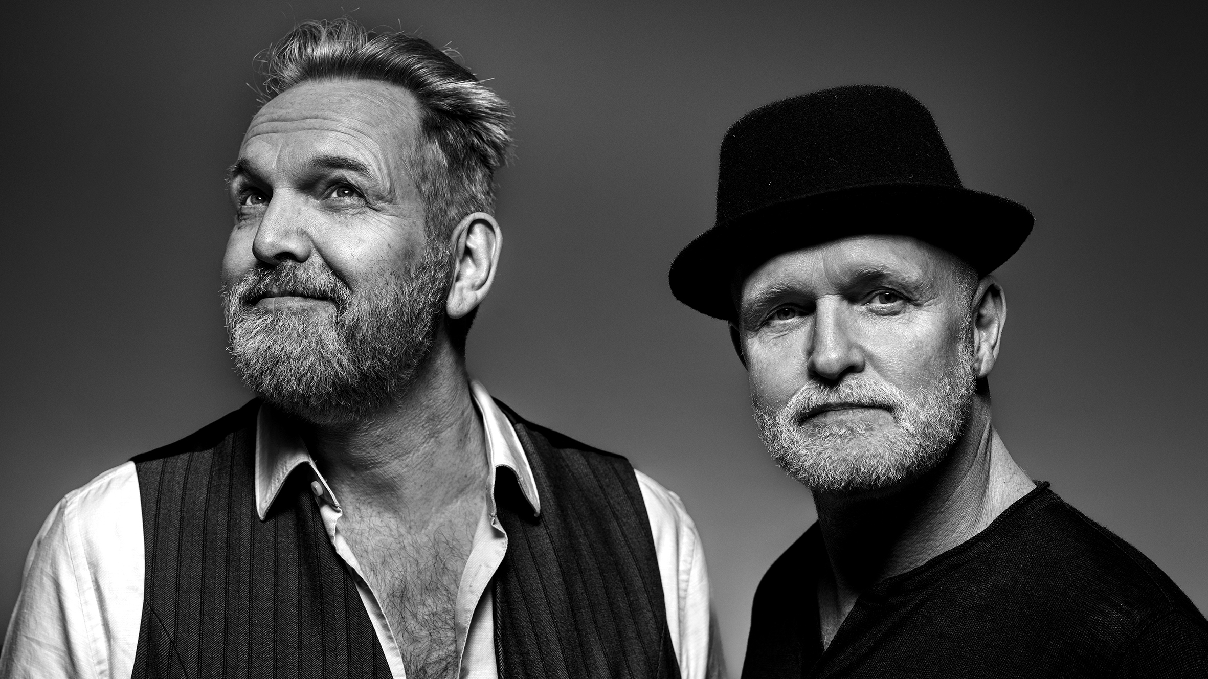 Twee oudere mannen met baarden, de linker zonder hoed en kijkend naar boven, de rechter met een hoed en een neutrale blik, portret in zwart-wit.