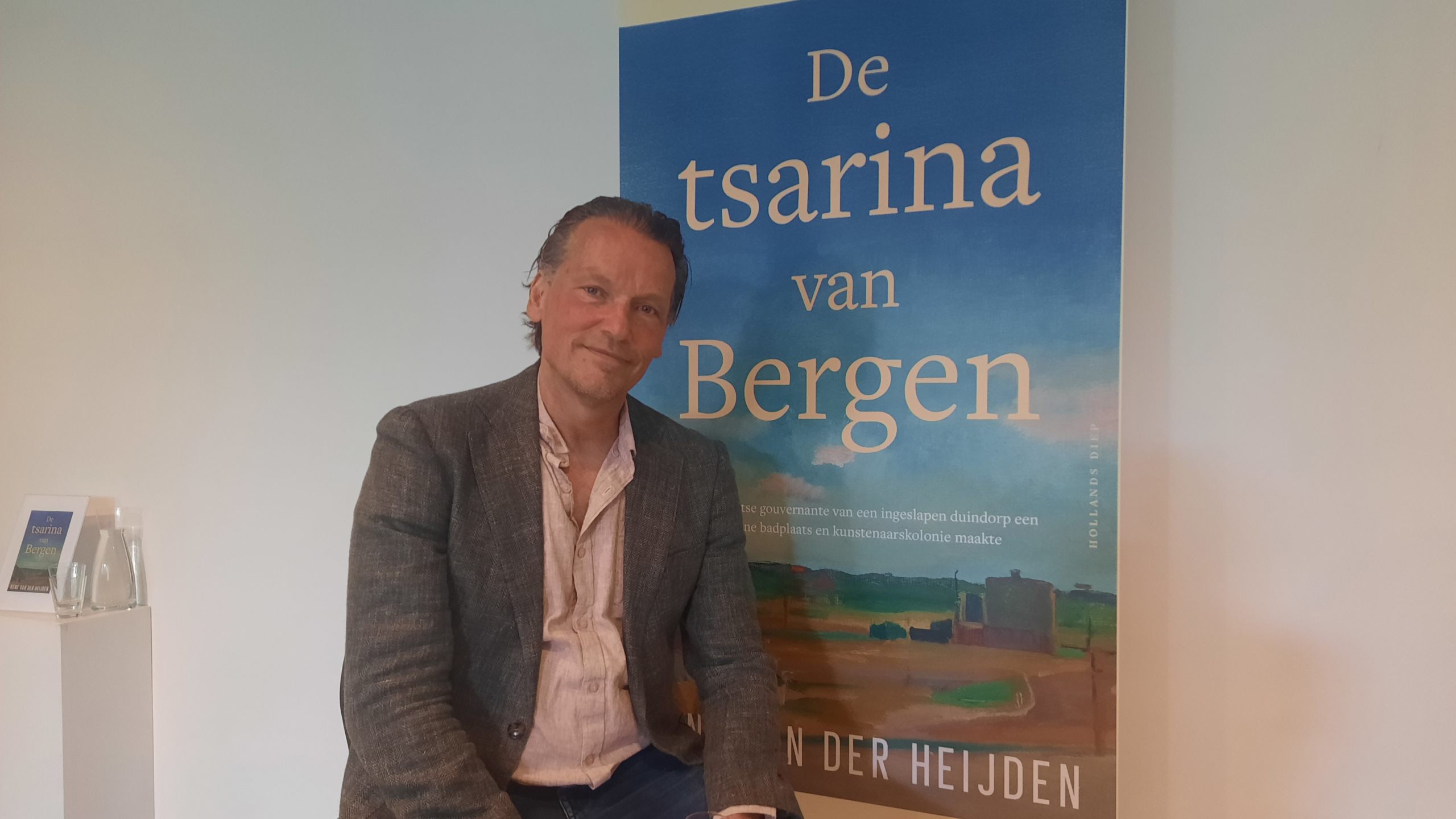 Man poseert voor een groot affiche van het boek 'De tsarina van Bergen'.